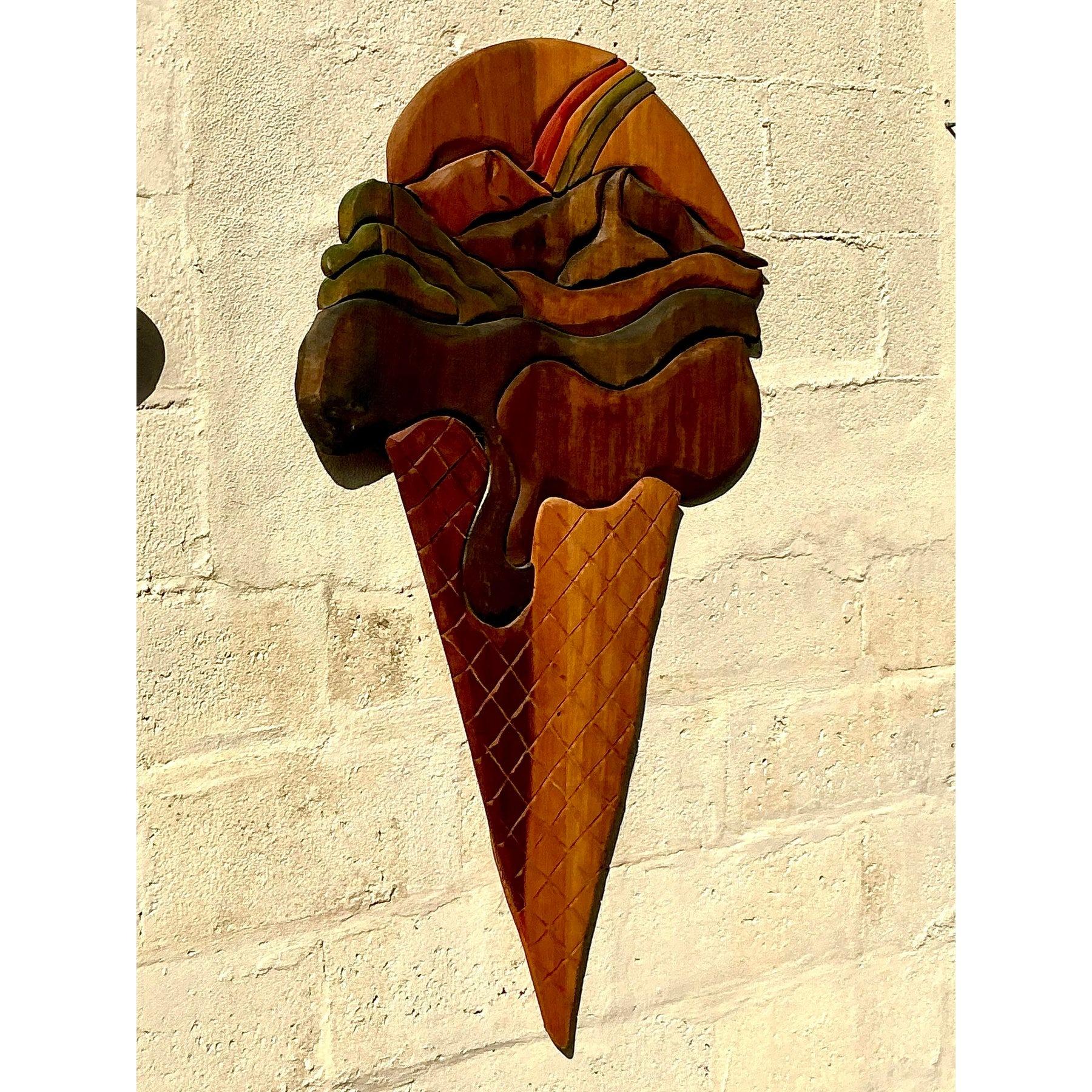 Diese skurrile und monumentale geschnitzte Eistüten-Skulptur versprüht Charme und Bohème-Flair. Das aus wunderschön gebeiztem Holz gefertigte Stück zeigt kunstvolle Schnitzereien, die die tropfende Schokolade und den strukturierten Waffelkegel zum