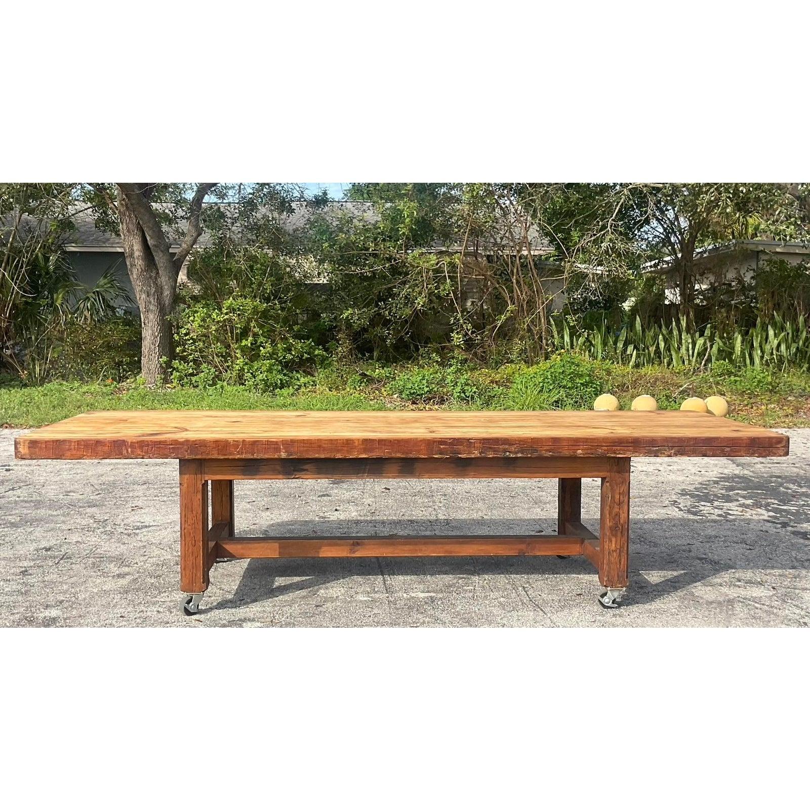 Discover the raw charm and expansive utility of this vintage monumental plank dining table, perfectly embodying a blend of Boho and Industrial aesthetics. Crafted from robust, beautifully aged wood planks, this table features a rustic top with