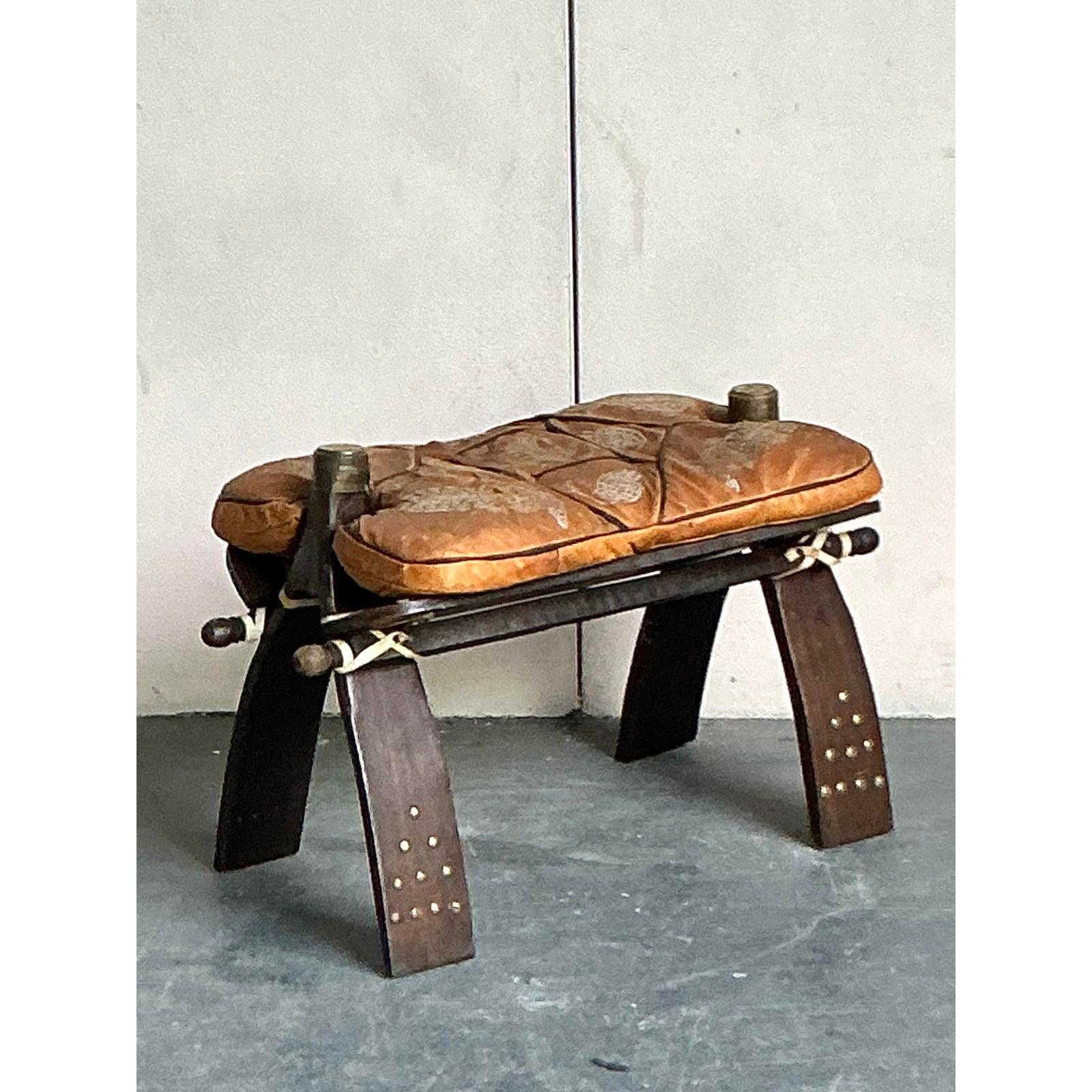 Adorn your home with the rich heritage and adventurous spirit of North Africa with this captivating vintage Moroccan camel stool. This unique piece is a work of art, meticulously crafted with hand-tooled leather in a rich shade of brown, showcasing