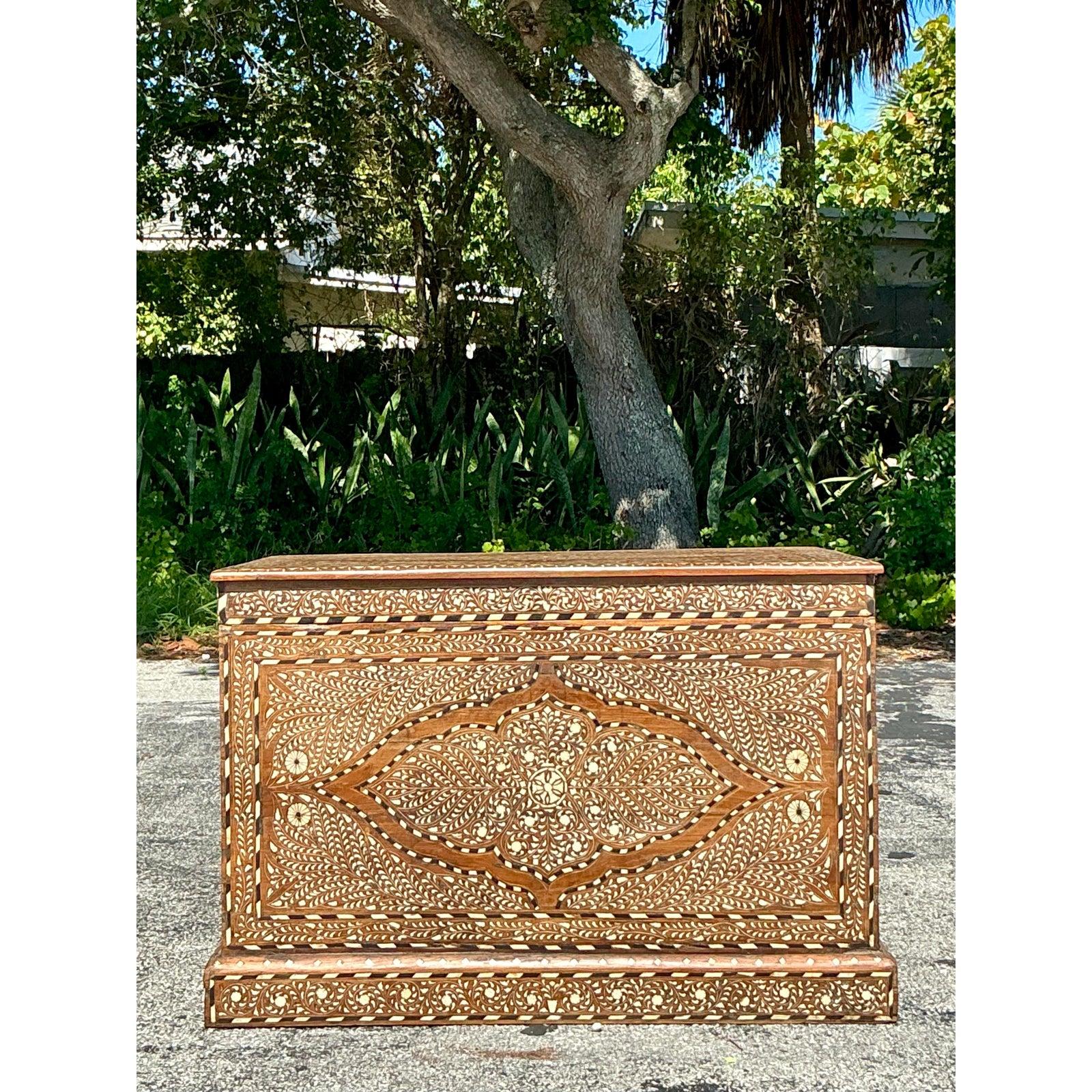 Unveil the captivating allure of this Vintage Boho Inlay Trunk, a testament to exquisite craftsmanship and global artistry. This Maranao chest, also known as an Anglo Indian Azira Inlay Trunk, showcases intricate bone inlay, creating a mesmerizing