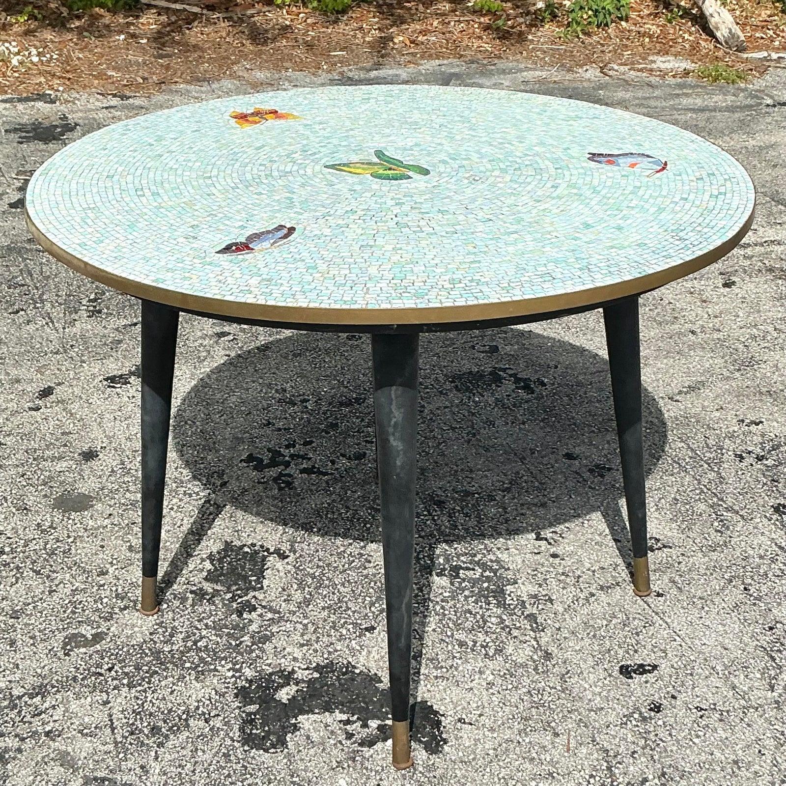 Elevate your dining experience with this captivating vintage mosaic tile dining table, showcasing an enchanting display of colorful butterflies and birds in a radiant circular design. Hand-laid iridescent tiles in soothing shades of aqua and mint
