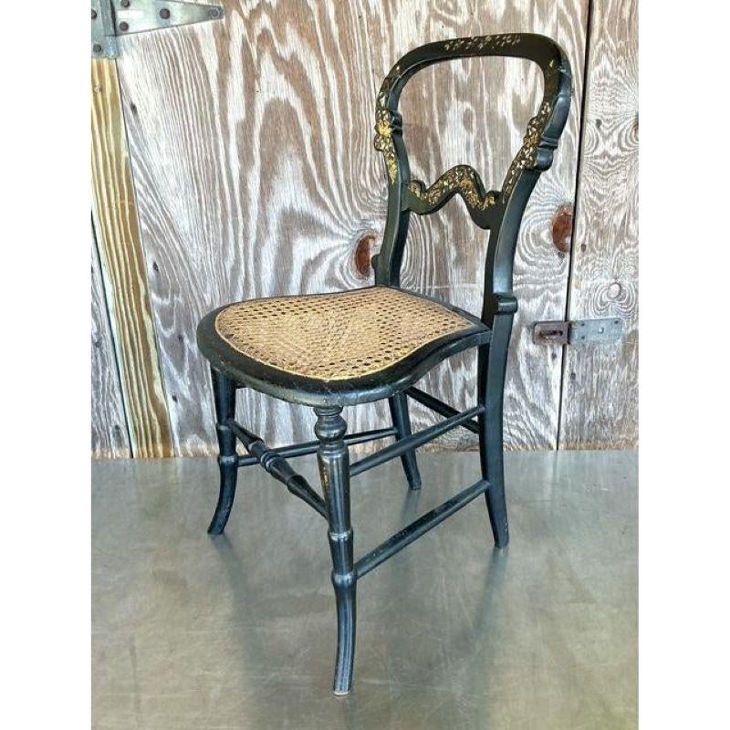 Entdecken Sie die fesselnde Anziehungskraft dieses exquisiten Akzentstuhls im Vintage-Stil, der sich durch eine aufwändige Perlmuttintarsie auszeichnet, die auf einer tiefschwarz lackierten Oberfläche schimmert, die wahrscheinlich über einer