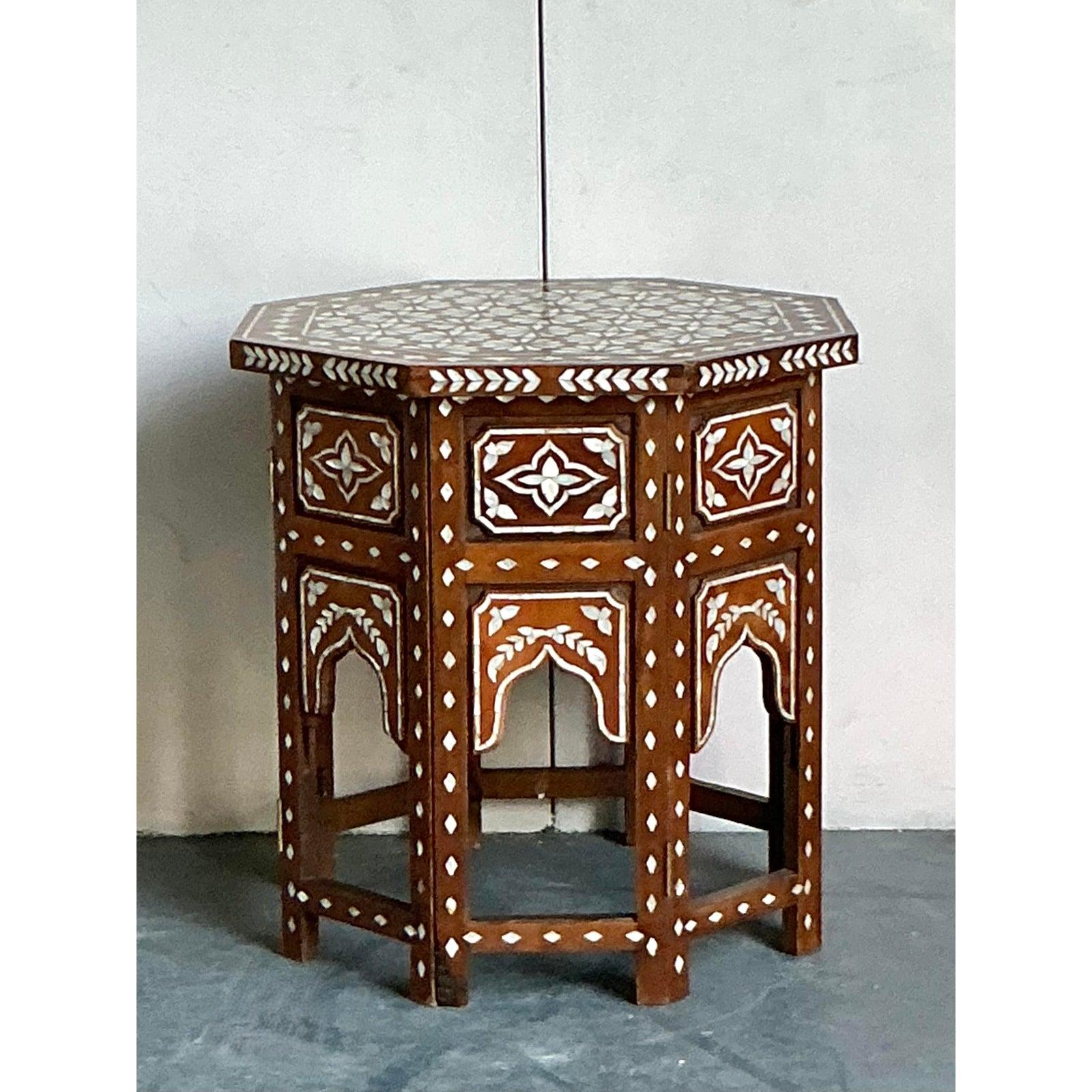 A true jewel of artisanal craftsmanship, this vintage octagonal side table is a stunning example of the intricate inlay traditions of the Middle East. Masterfully handcrafted from warm-toned wood, the table is lavishly adorned with hand-set pieces