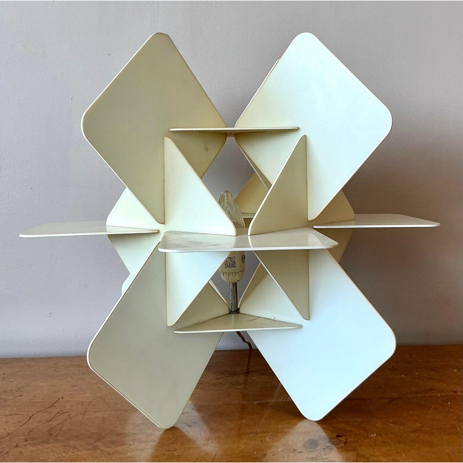 Illuminate your space with the sculptural brilliance of this vintage origami-style table lamp. A masterpiece of geometric design, this piece features a complex structure of interlocking resin panels, folded to create a dynamic, star-like form that