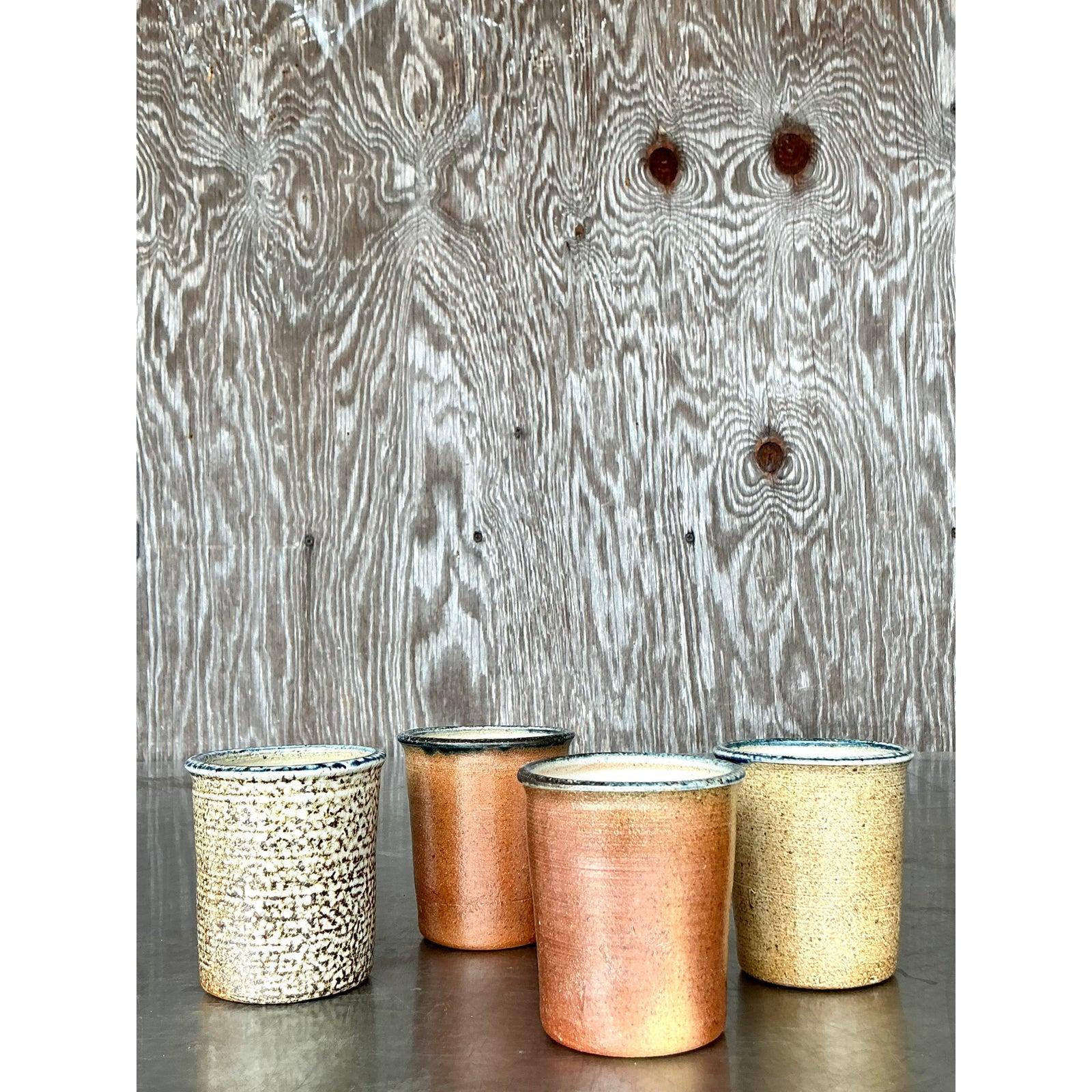 Celebrate the beauty of artisanal craftsmanship with this charming set of four vintage studio pottery cups. Each cup features unique variations in glaze and texture—from speckled cream to earthy burnt sienna—reflecting the hand-thrown nature of