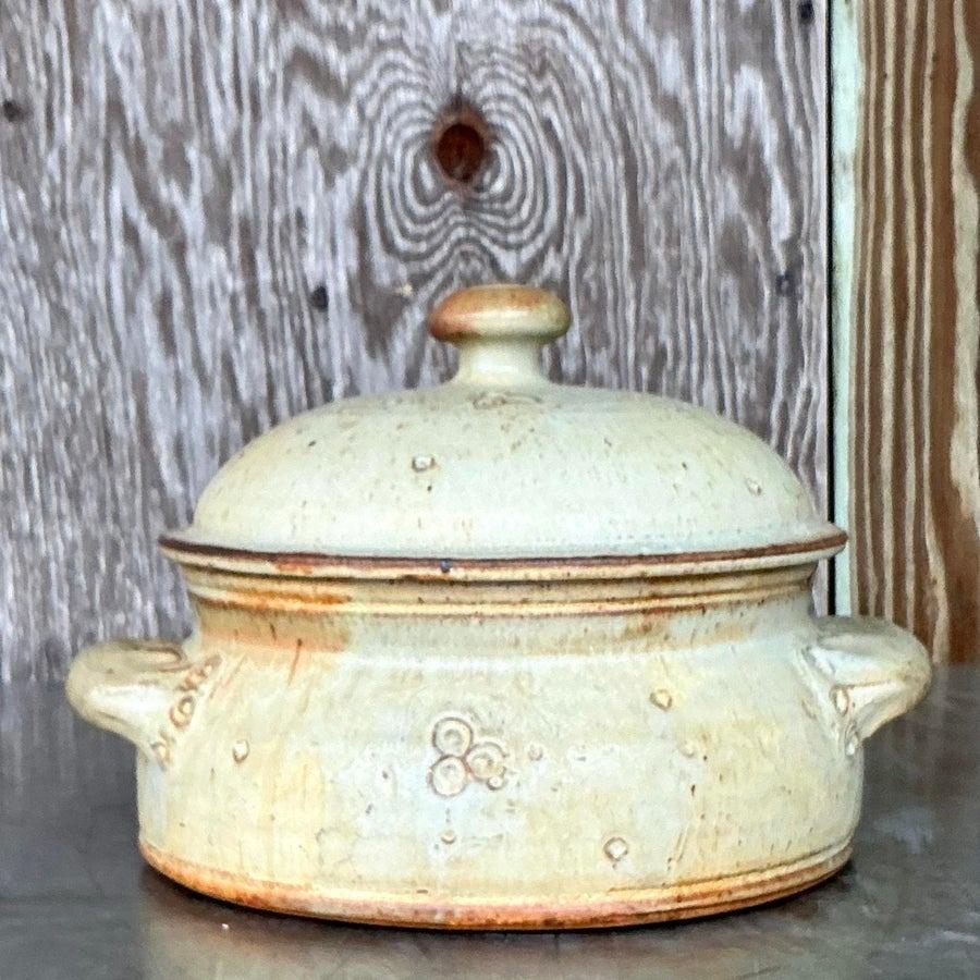 Elevate your kitchen or dining space with this charming vintage studio pottery lidded bowl. Featuring a beautifully rustic glaze in warm earthy tones, this handcrafted piece showcases intricate, boho-inspired details, making it a unique addition to