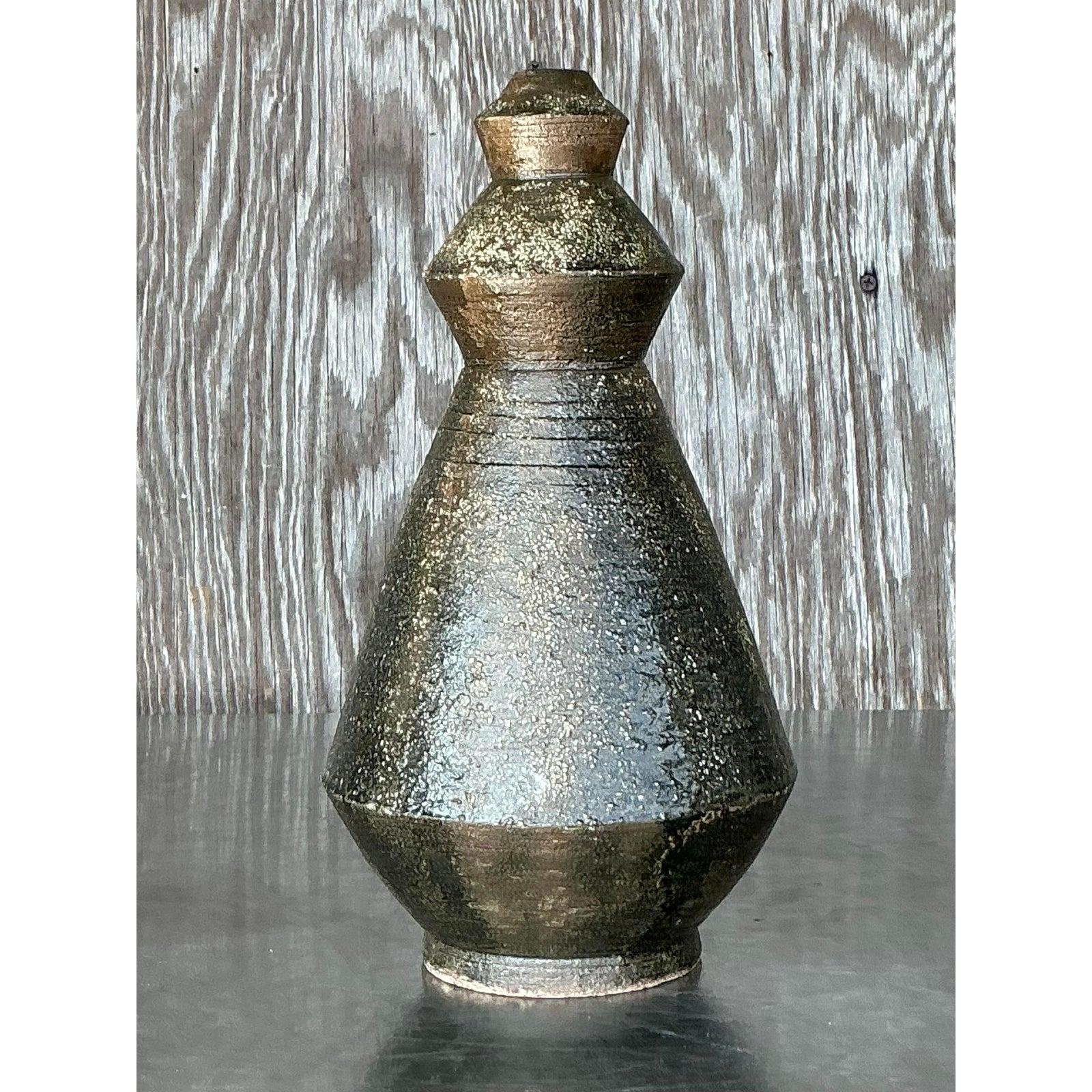 Questo sorprendente vaso vintage in Studio Pottery è una vera e propria testimonianza di maestria artigianale, caratterizzata da una forma geometrica unica con intricati dettagli segnati. Il suo smalto ricco e strutturato in profonde tonalità