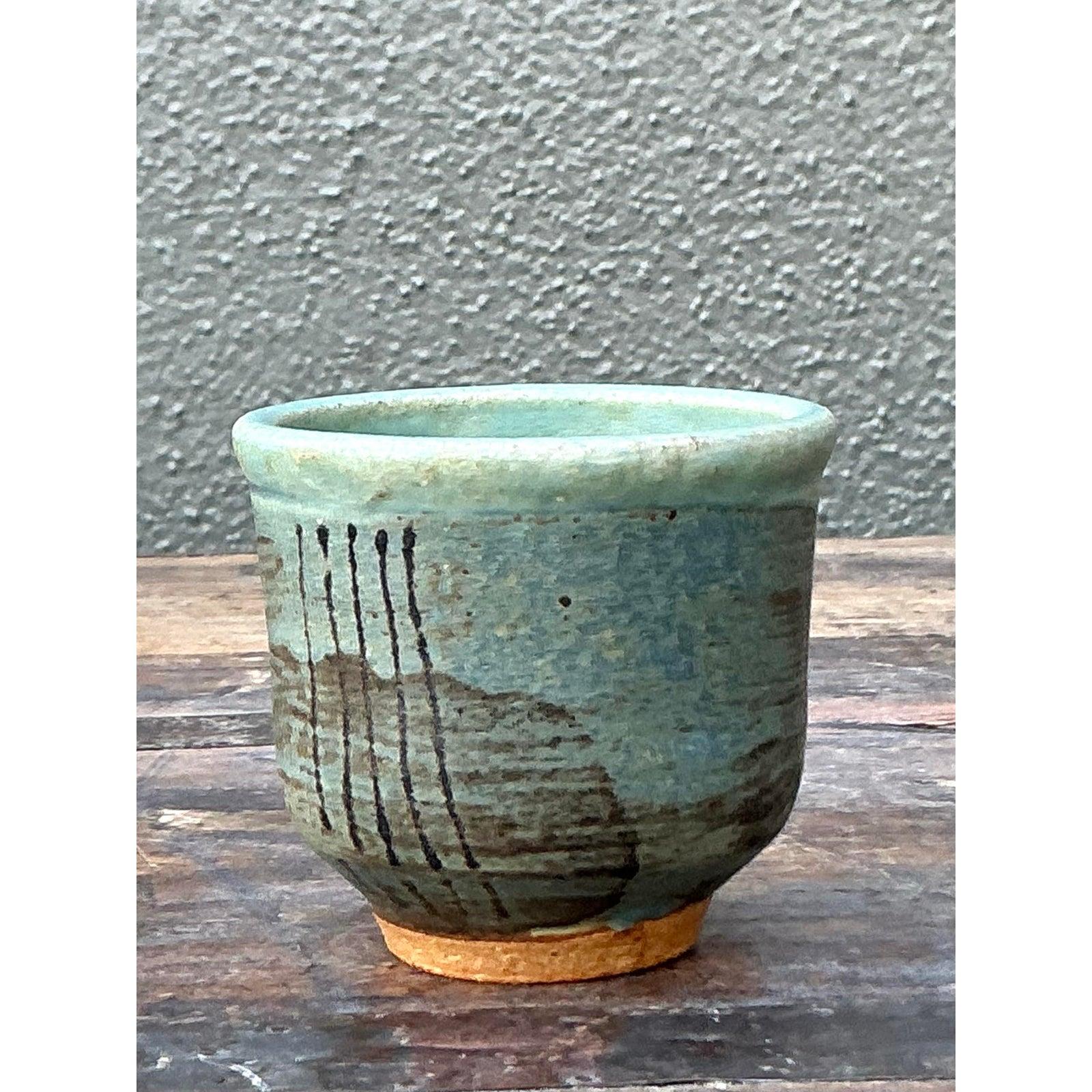 Scopri il fascino sereno della ceramica artigianale con questo delizioso vaso vintage in Studio Pottery. Il pezzo è caratterizzato da uno smalto verde mare opaco che evoca le tonalità tranquille delle acque costiere. È artisticamente accentuata da