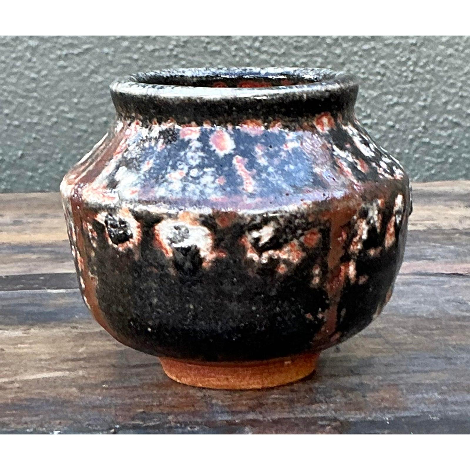 Scopri la bellezza robusta del design organico con questo affascinante vaso vintage in Studio Pottery. Esempio lampante dell'estetica brutalista, questo piccolo recipiente è caratterizzato da uno smalto 