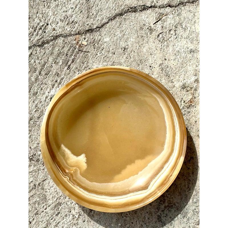 Questa ciotola d'epoca in onice è un esempio straordinario dell'arte della natura e della maestria senza tempo. Scolpita in una pietra ricca di venature, presenta calde tonalità della terra in vortici di miele, crema e ambra, creando un'estetica