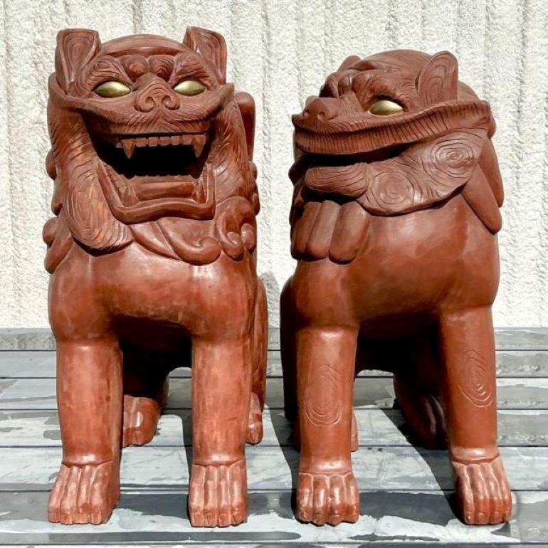 Fai un'affermazione audace con questa coppia di cani da caccia vintage boho monumentali in legno dipinto. Questi guardiani intagliati in modo intricato sono impreziositi da colori vivaci e da una lavorazione artigianale dettagliata, che incarna sia