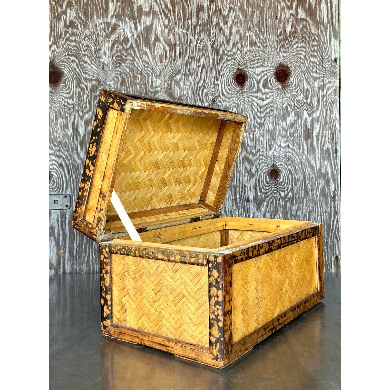 Infusez votre espace avec un charme rustique et une élégance naturelle avec cette boîte à couvercle en rotin de parquet boho vintage. Avec son motif à chevrons magnifiquement tissé et ses garnitures en bambou foncé et vieilli, cette pièce unique