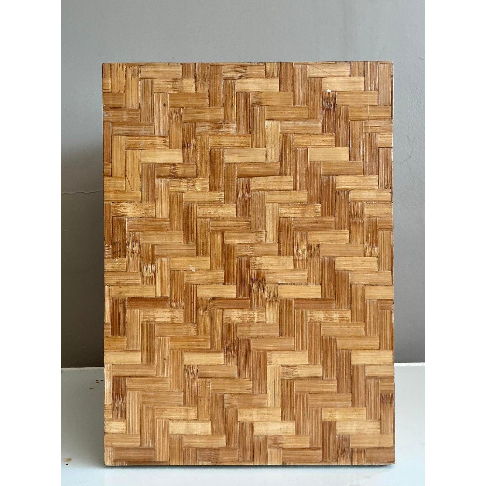 Infuse your space with a touch of organic texture and bohemian flair with this handsome vintage pedestal. Masterfully wrapped in a woven rattan veneer, its defining feature is the stunning parquet or basketweave pattern that covers all sides,