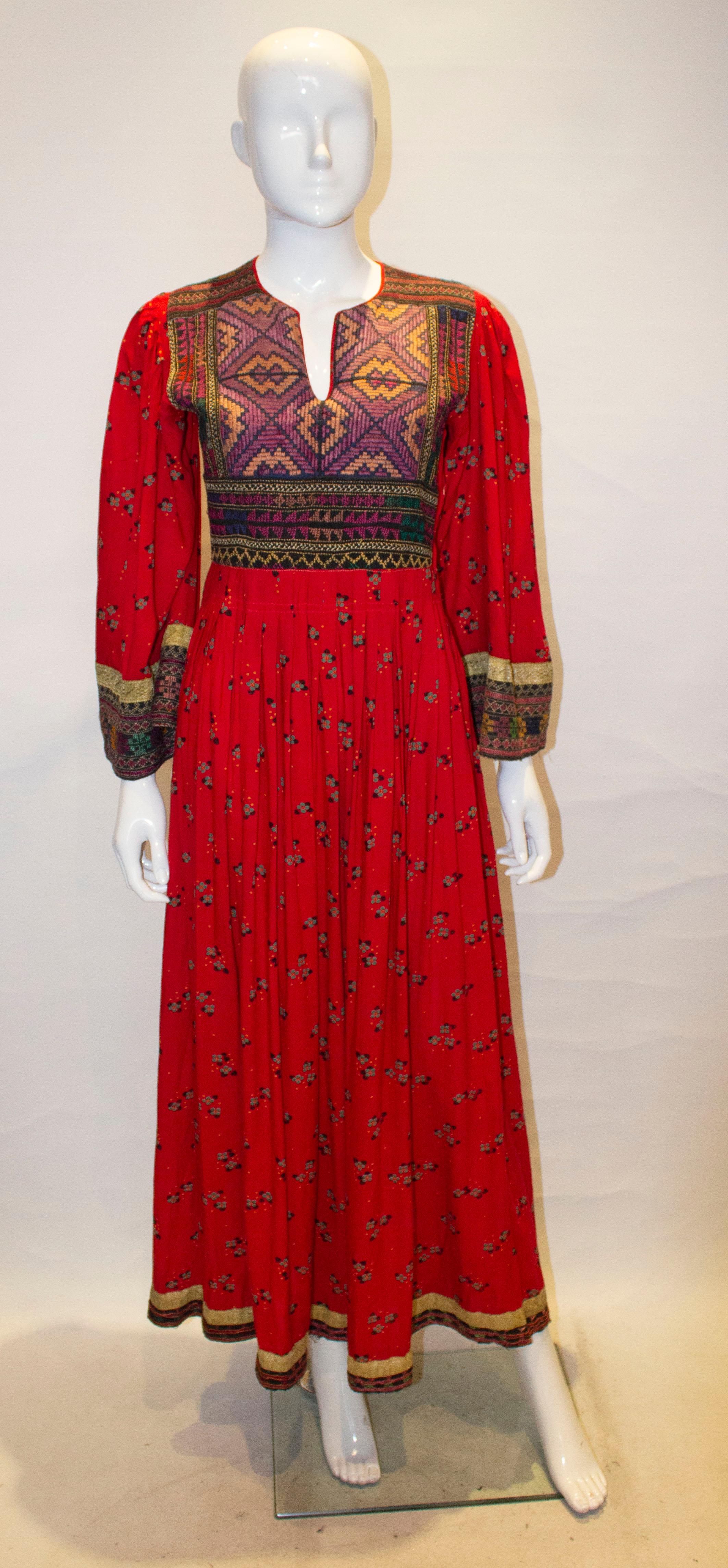 A fun vintage dress,with embroidery detail on the front and cuffs. The dress has a round neckline with a v neckline. It has a side zip opening and pleats below the bust.