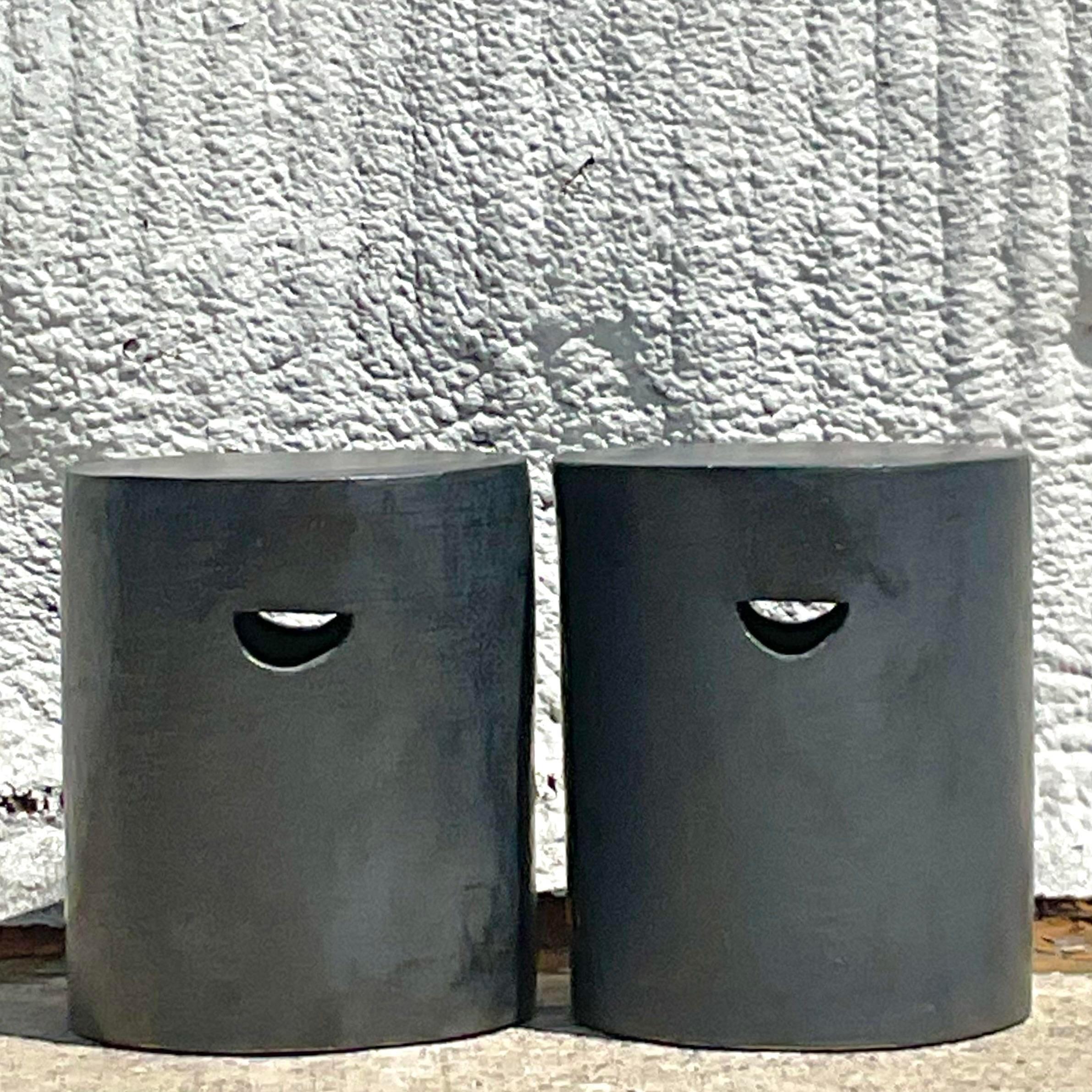 An incredible pair of vintage Boho low stools. A chic cylinder shape with cut out handles for easy movement. The most beautiful patinated finish in a deep charcoal grey. Acquired from a Palm Beach estate.