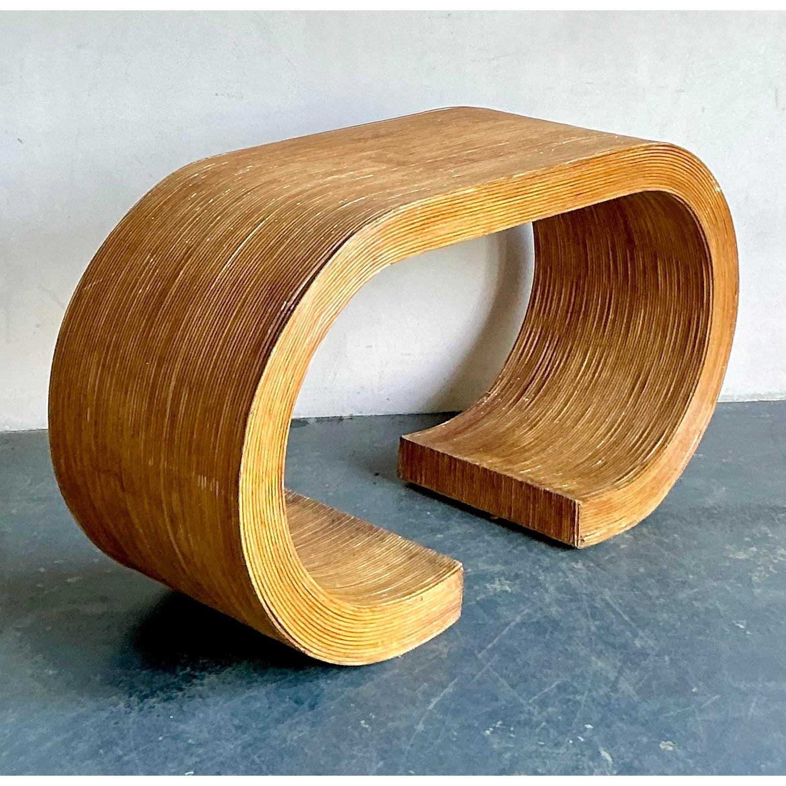 This exceptional console table is a striking testament to textural and minimalist design, defining the sleek Coastal Modern aesthetic of the 1970s. Constructed entirely of tightly stacked and curved pencil reed rattan, the piece achieves a dramatic,