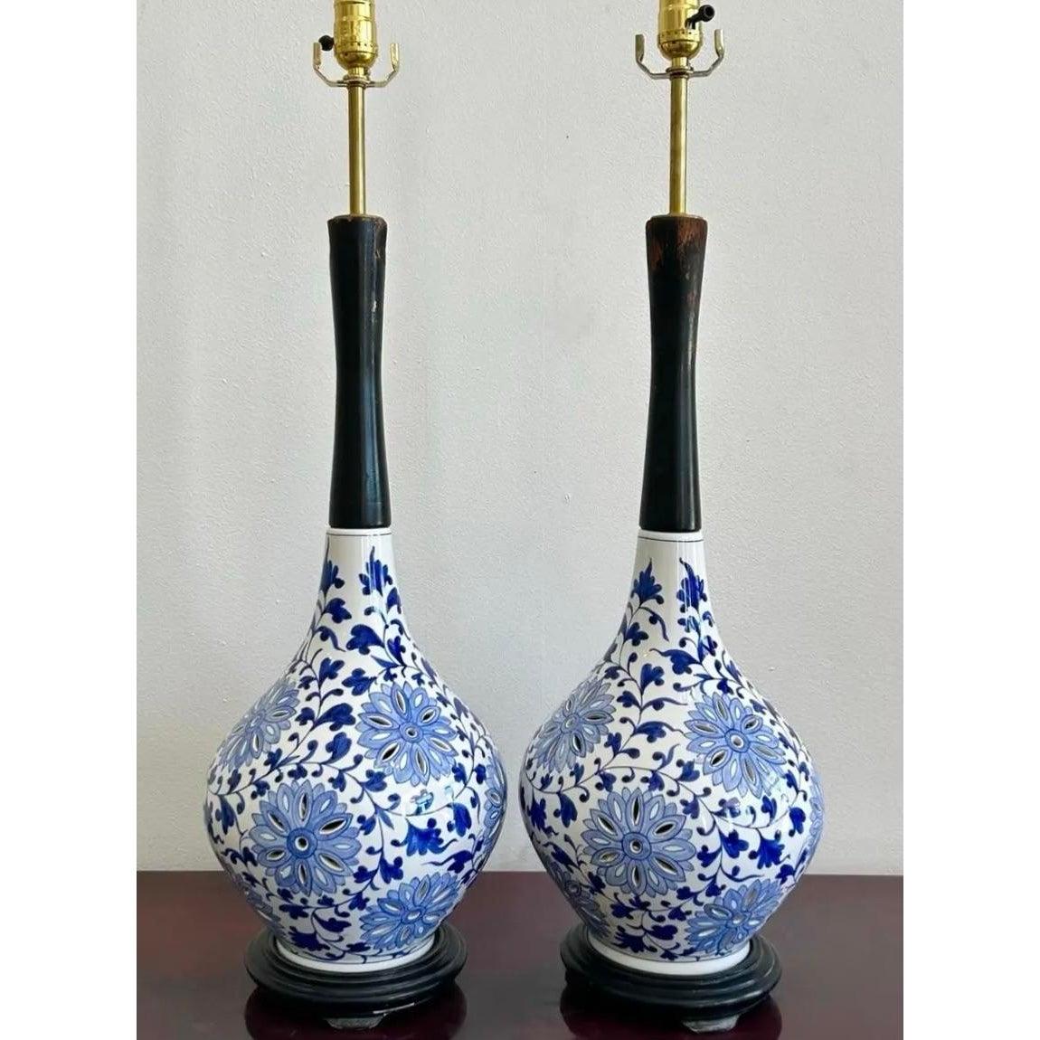 Questa straordinaria coppia di lampade da tavolo presenta basi bulbose in ceramica ornate da intricati motivi floreali blu su sfondo bianco, che richiamano i disegni tradizionali. Ogni lampada si trasforma in un elegante collo in legno scuro