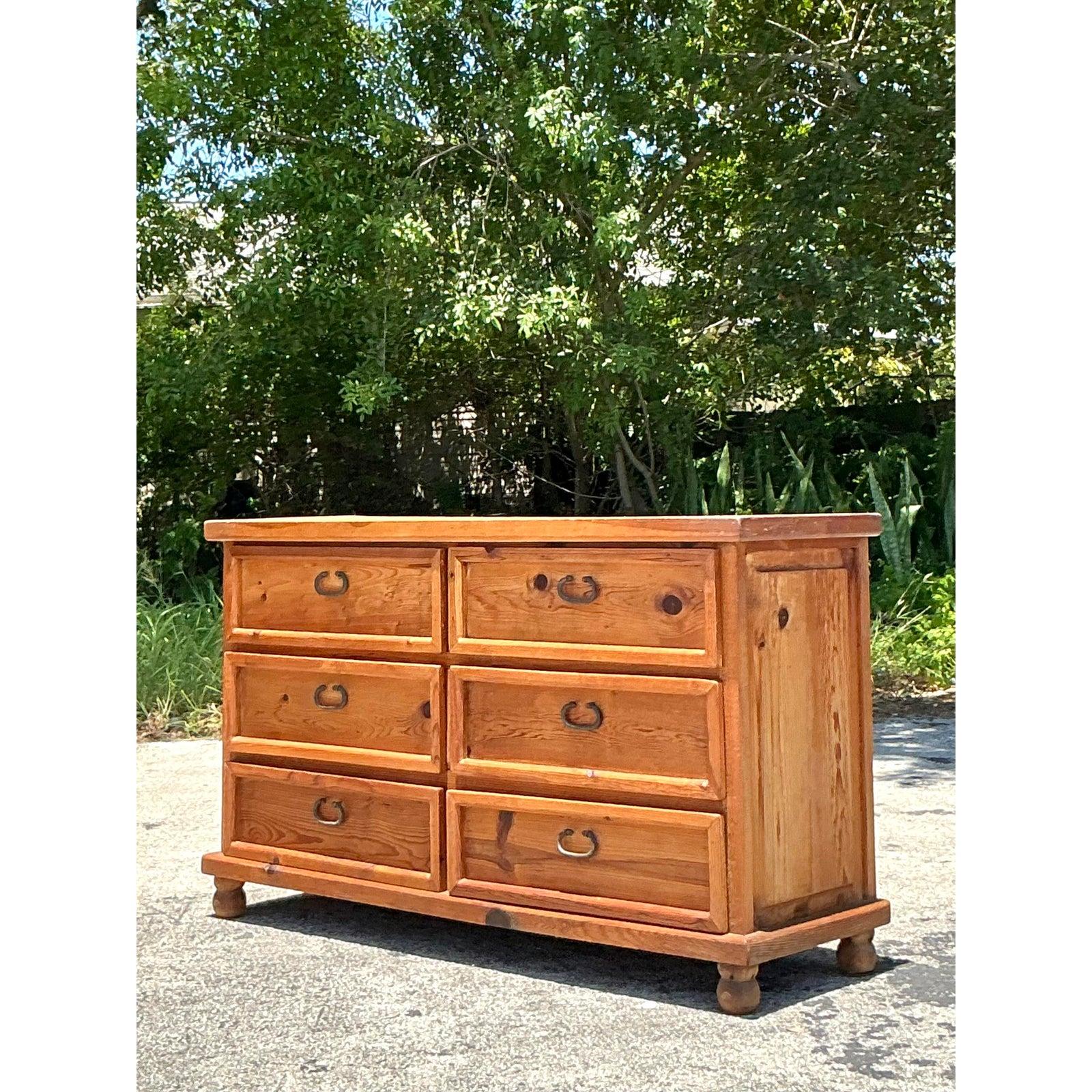 Embrace the serene beauty of natural materials and functional design with this charming Vintage Boho Pine Dresser. Crafted from solid pine, this piece exudes a warm, inviting character, with the wood's natural grain and charming knots lending an