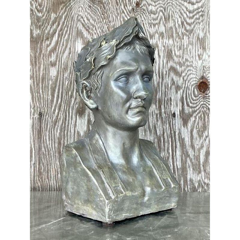 Introduci un tocco di grandezza d'altri tempi nella tua casa con questo sorprendente busto neoclassico vintage. Ispirato alla scultura classica greco-romana, questo pezzo presenta un volto sereno coronato da una tradizionale corona d'alloro,