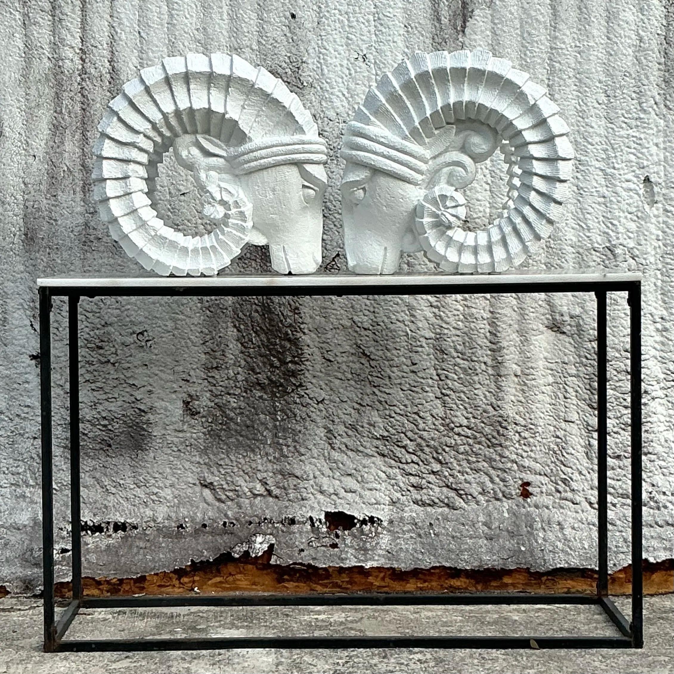 Questa splendida coppia di teste di ariete in gesso vintage Boho aggiunge un tocco architettonico a qualsiasi ambiente esterno o interno. Ogni pezzo presenta intricati dettagli scultorei con linee geometriche e audaci che accentuano le iconiche