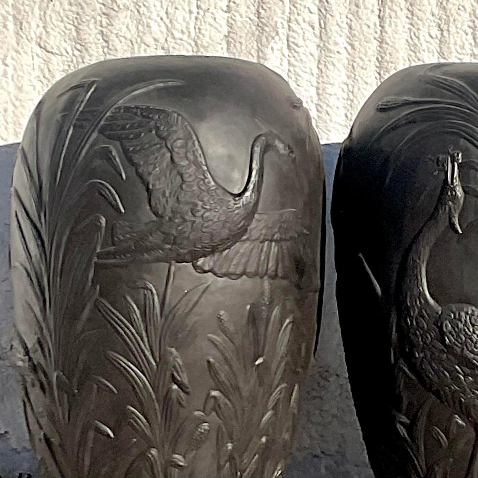 A striking pair of vintage Boho plaster over fiberglass urns. A chic tropical relief with cranes and foliage. Perfect as is or paint them any color to suit your project. Acquired from a Palm Beach estate. 