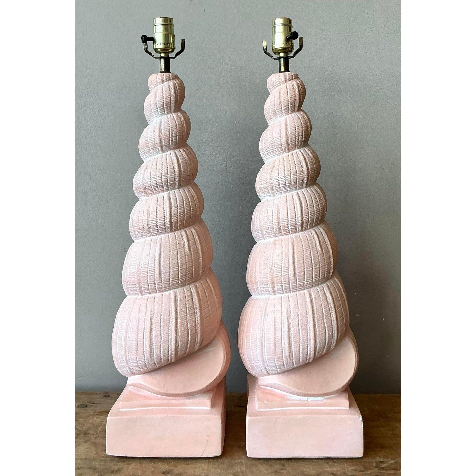 Embrace the soft, sculptural elegance of the 1980s Postmodern revival with this charming pair of vintage plaster shell lamps. Modeled after spiraling auger shells, these table lamps feature a tactile, ribbed texture and a soft, matte peach-blush