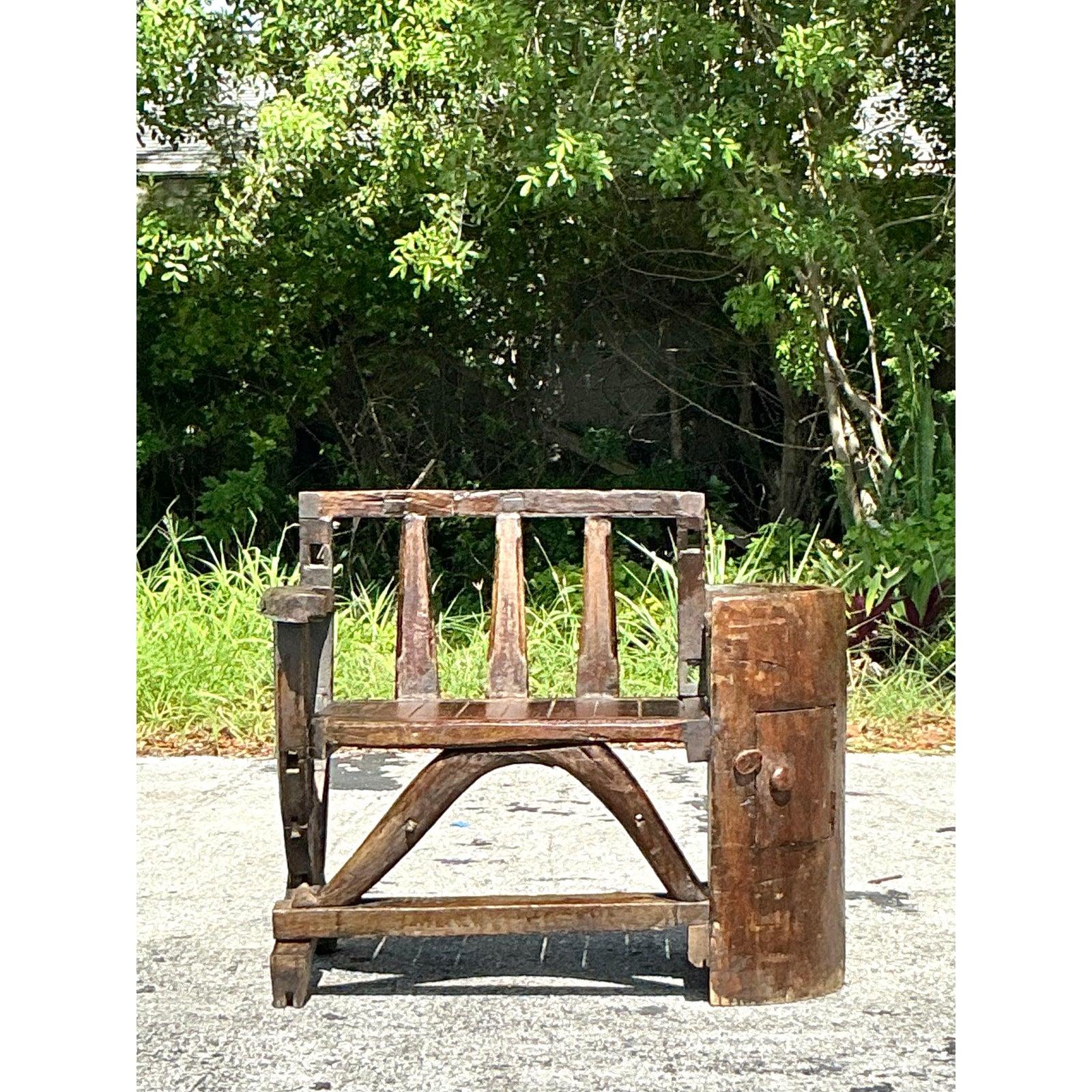 Evoke a sense of rugged artistry and singular character with this extraordinary vintage primitive bench. Its most striking feature is the robust, repurposed barrel-like element forming one side, complete with a charming small hatch, lending an air
