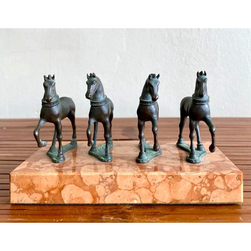 Un tributo senza tempo alla forza e al movimento, questa scultura in miniatura presenta quattro cavalli in bronzo fuso a metà del passo, ognuno con una postura unica, montati su una base di marmo dalle calde venature. Ricordando i fregi equestri