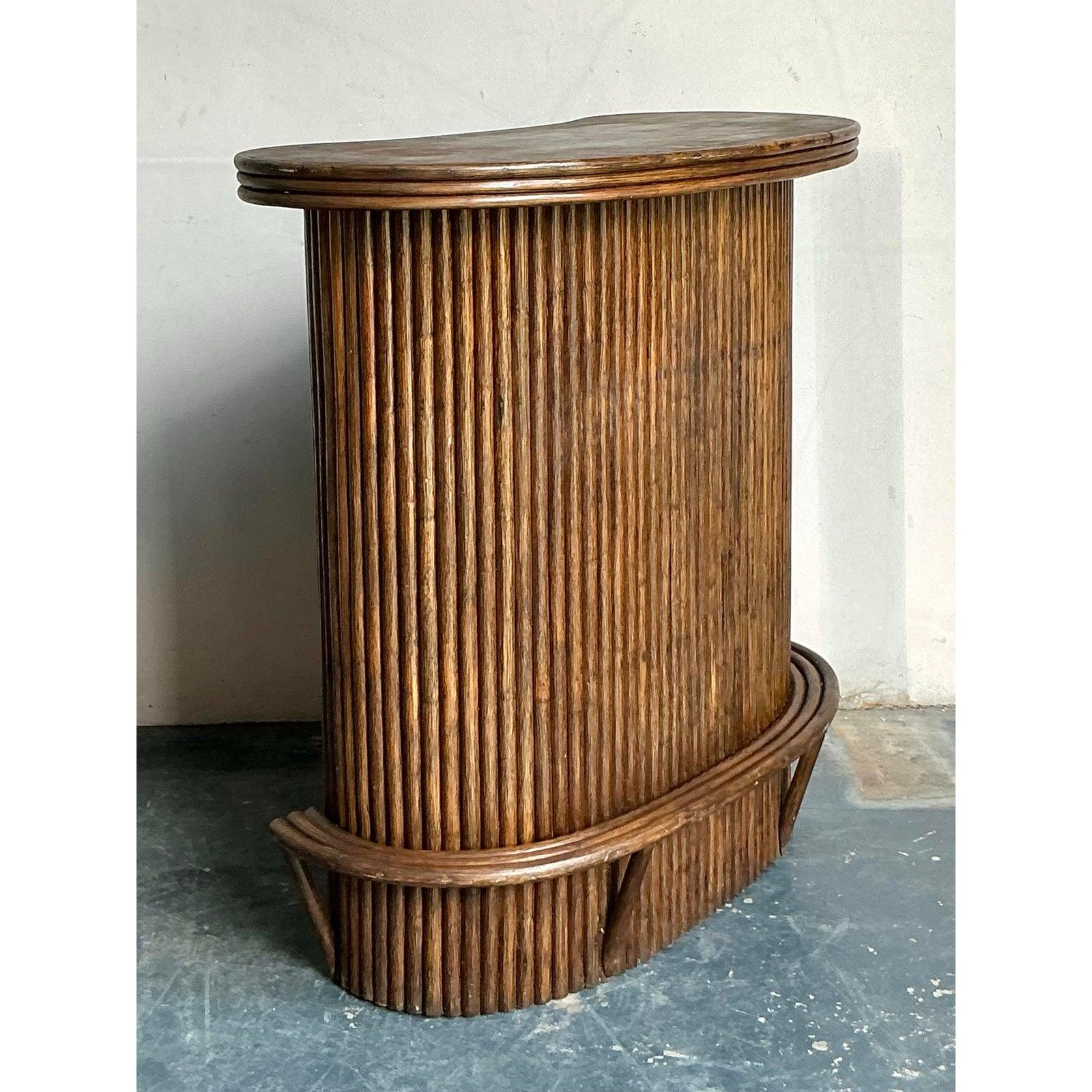 This exquisite vintage dry bar captures the spirited luxury and organic texture of the late Mid-Century era, specifically channeling the popular Boho Chic and Tropical aesthetics of the 1970s. The piece features a striking cylindrical form defined