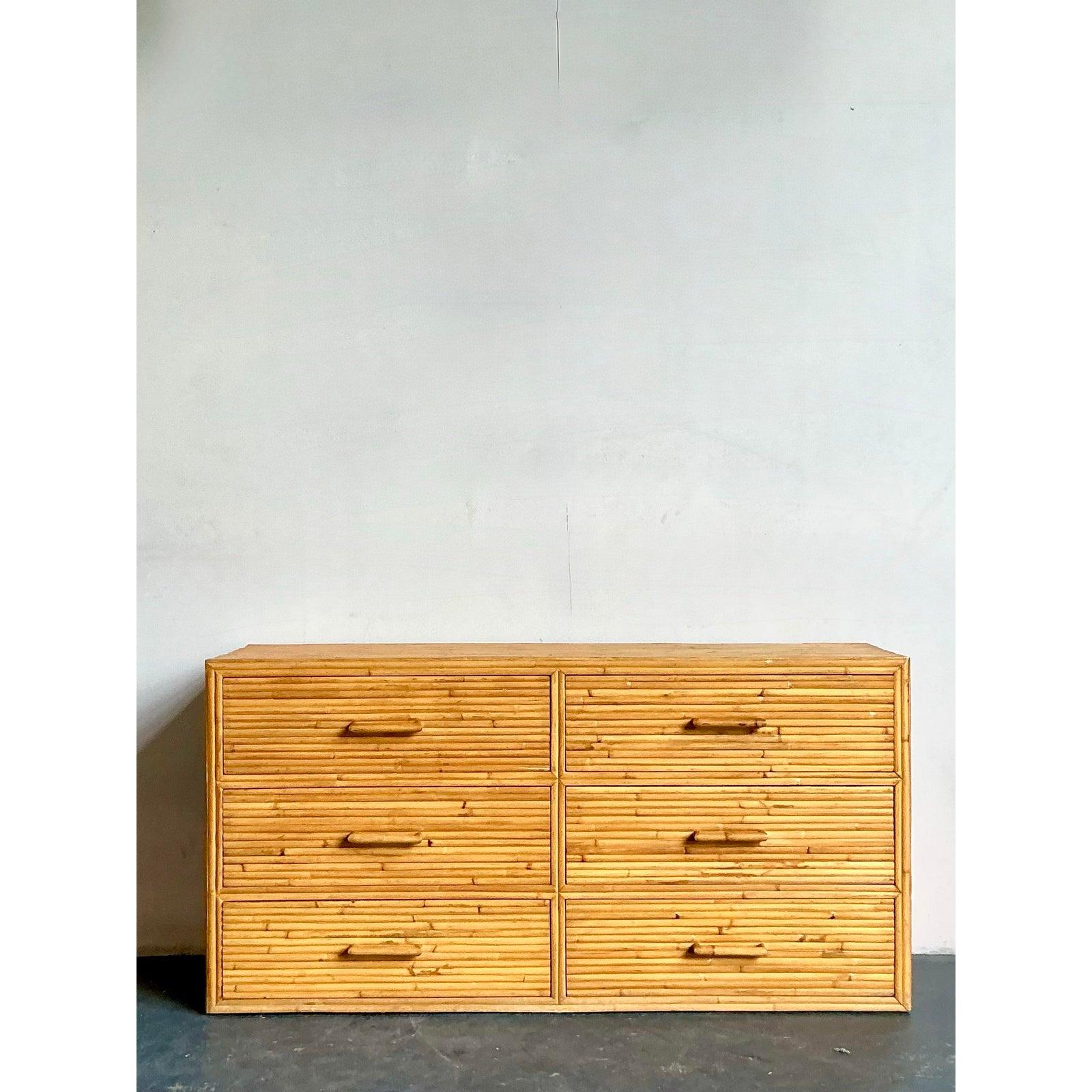 Ti presentiamo un affascinante comò vintage a sei cassetti in rattan Boho, un pezzo eccezionale che sposa magnificamente l'estetica rilassata della vita costiera con le linee pulite del design del Mid-Century Modern. Questa cassettiera è realizzata