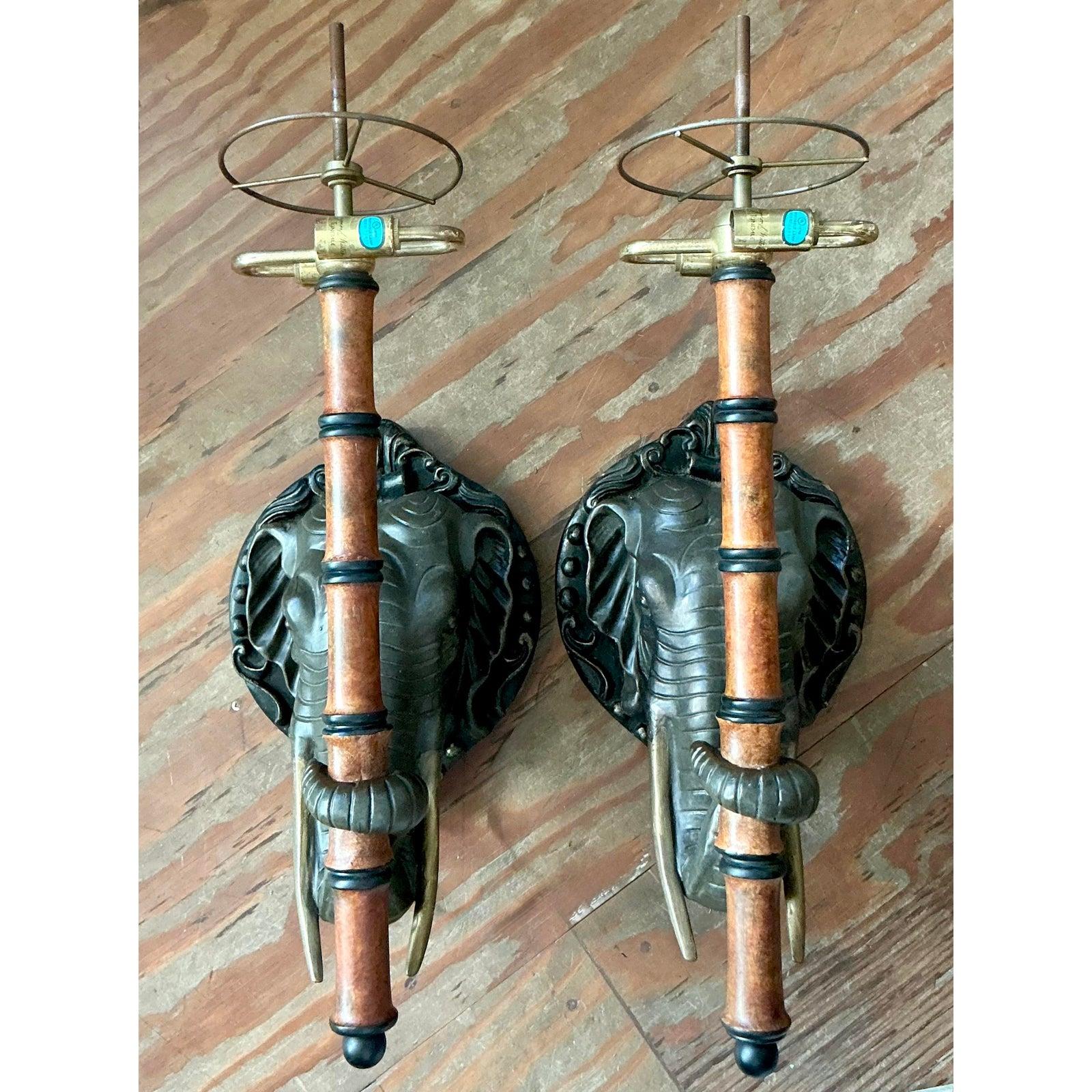 This dramatic pair of vintage wall sconces makes an unforgettable statement, embodying the bold, maximalist aesthetic of Hollywood Regency with a distinctive exotic, safari flair. Each fixture features a meticulously cast elephant head mount,