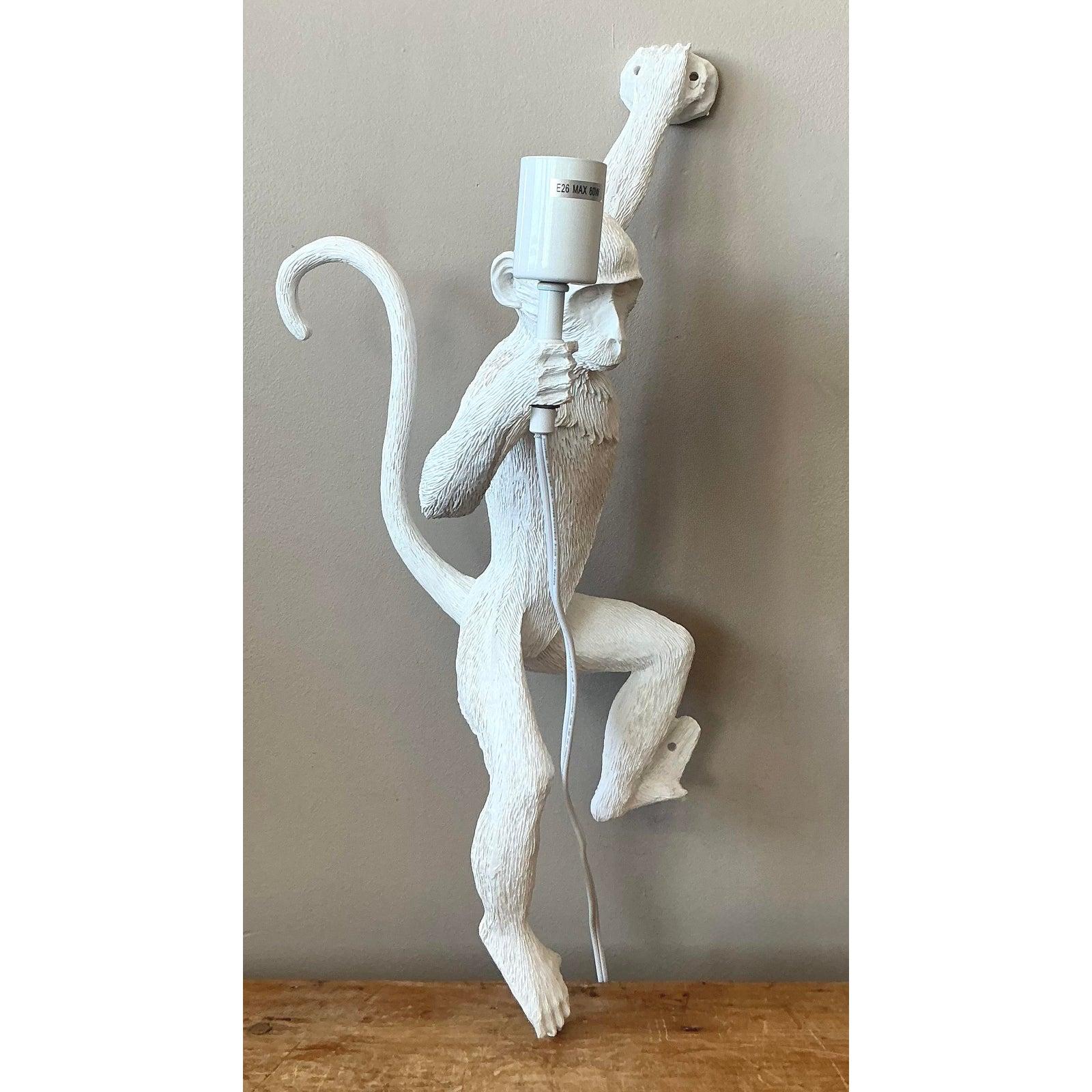 Inject a dose of playful charm and personality into your space with this delightful figural monkey wall sconce. Crafted from durable resin with a crisp, matte white finish, this sculptural lamp depicts a lifelike monkey in a climbing pose, holding a