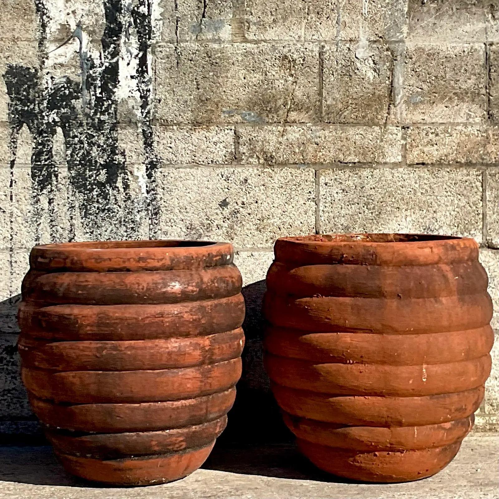 A spectacular pair of vintage boho planters. A chic ribbed design in a heavy terracotta. Beautiful all over patina from time. Acquired from a Palm Beach estate.

The planters are in great vintage condition. Minor scuffs and blemishes appropriate