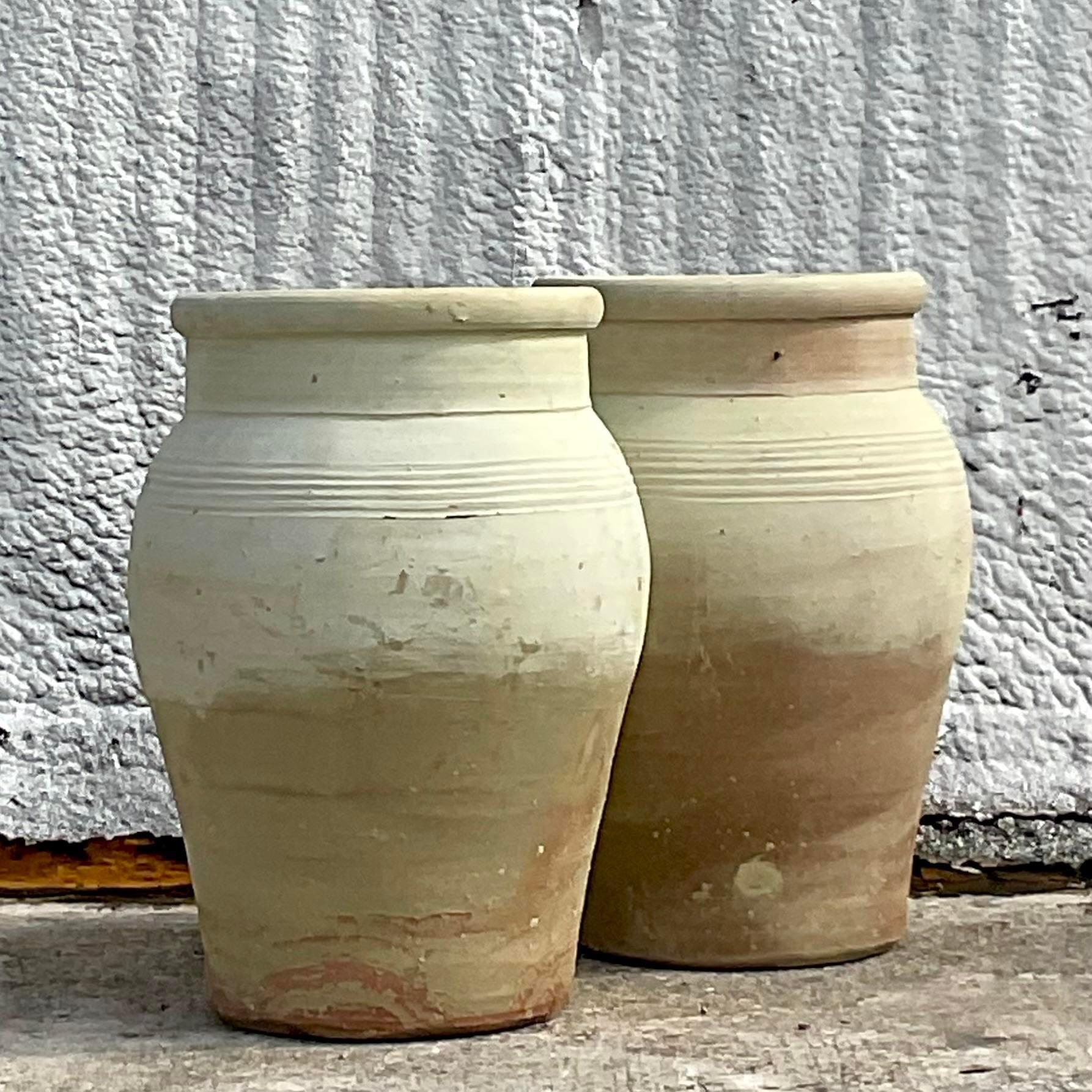 A stunning pair of vintage ripple band Boho urns. A chic terra cotta with a gradient layer of paint. An all over patina from time. On hole drilled for drainage. Acquired from a Palm Beach estate. 