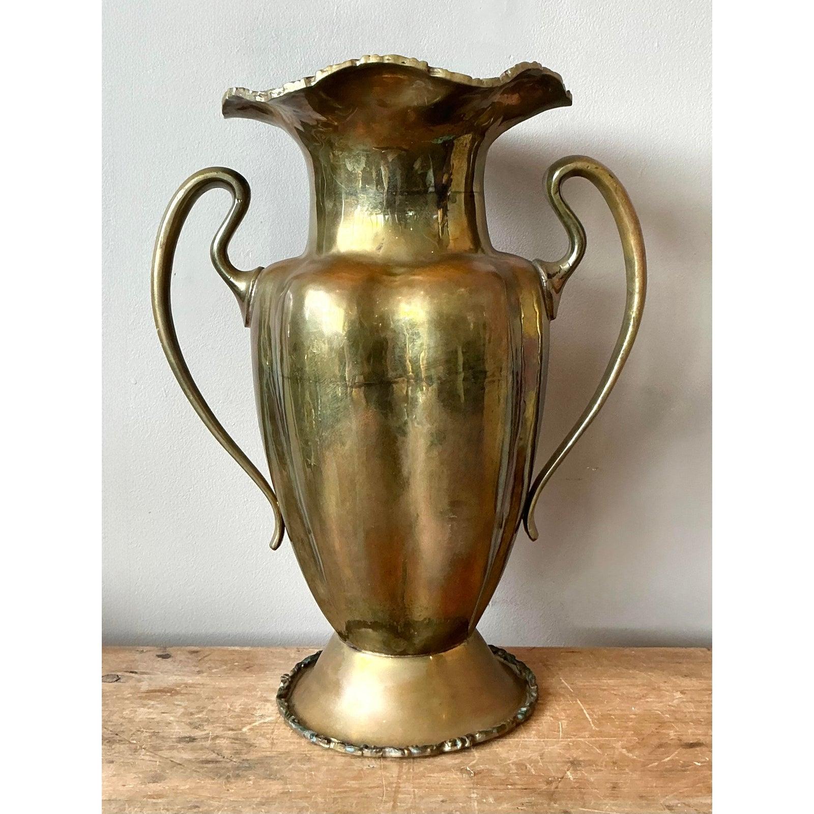 Questo magnifico vaso a urna d'epoca offre un punto focale sofisticato per qualsiasi stanza, unendo la grandezza storica al fascino rustico. Realizzato in ottone massiccio, il vaso presenta un'ispirazione classica neoclassica con una silhouette