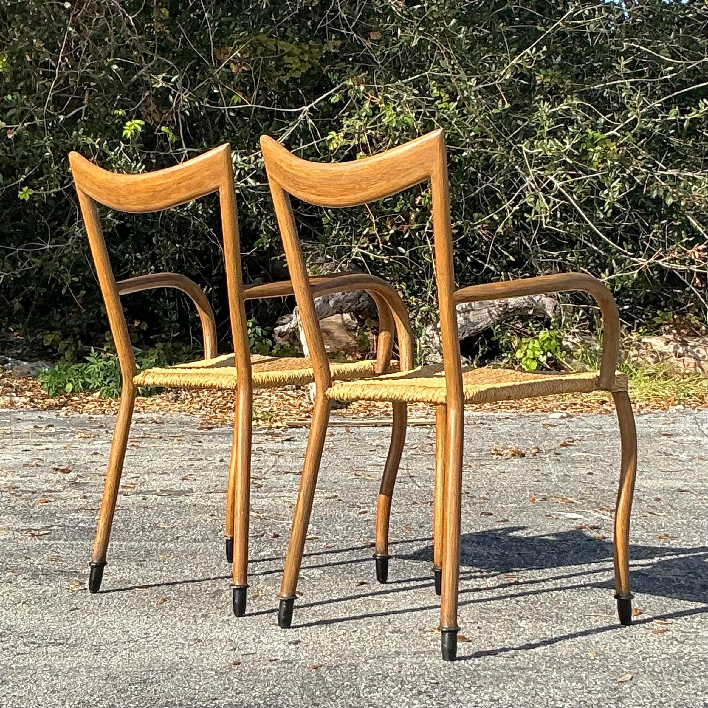 Une paire intemporelle de chaises à accoudoirs Vintage By By, avec des sièges en jonc tissé naturel et des cadres en bois élégamment courbés. Ces chaises dégagent un charme rustique et une élégance bohème, ce qui les rend parfaites pour les salles à