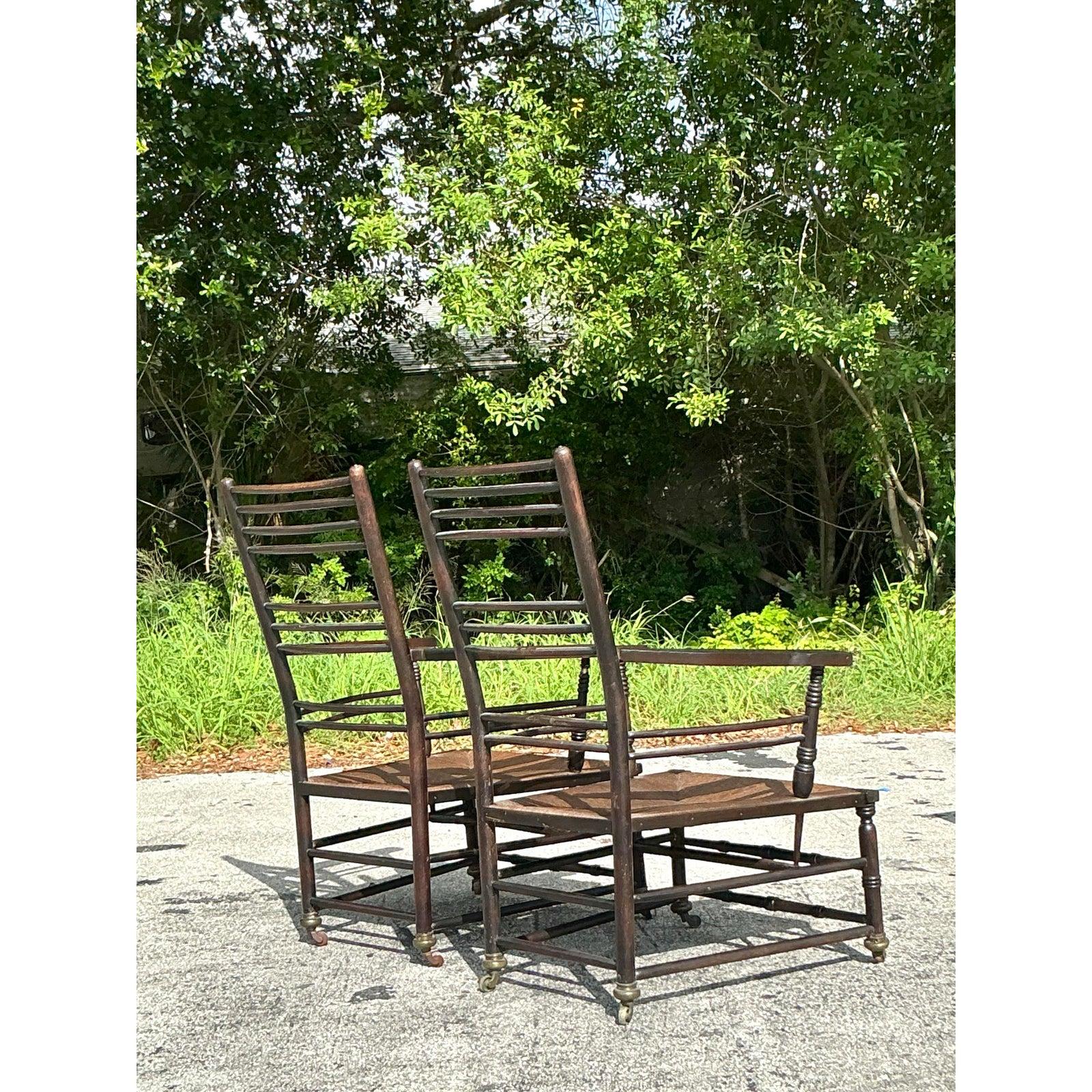 Embrace the timeless allure of English country charm with this exceptional pair of Vintage Rush Seat Sussex Lounge Chairs. Crafted from dark, rich wood and featuring classic spindle or ladder-style backs, these chairs evoke the rustic elegance