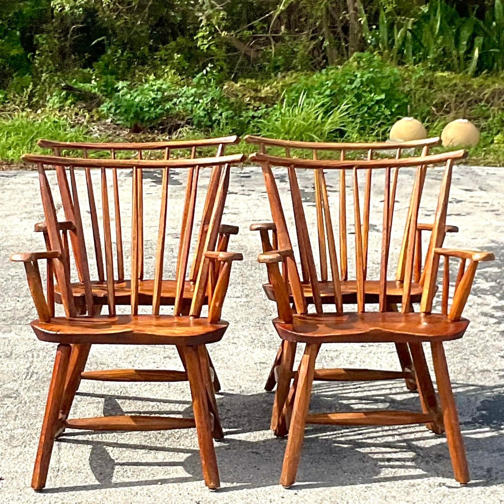 A fantastic set of four vintage Boho dining chairs. A chic primitive hand carved design with a spindle back design. Beautiful all over patina from time. Acquired from a Palm Beach estate.
