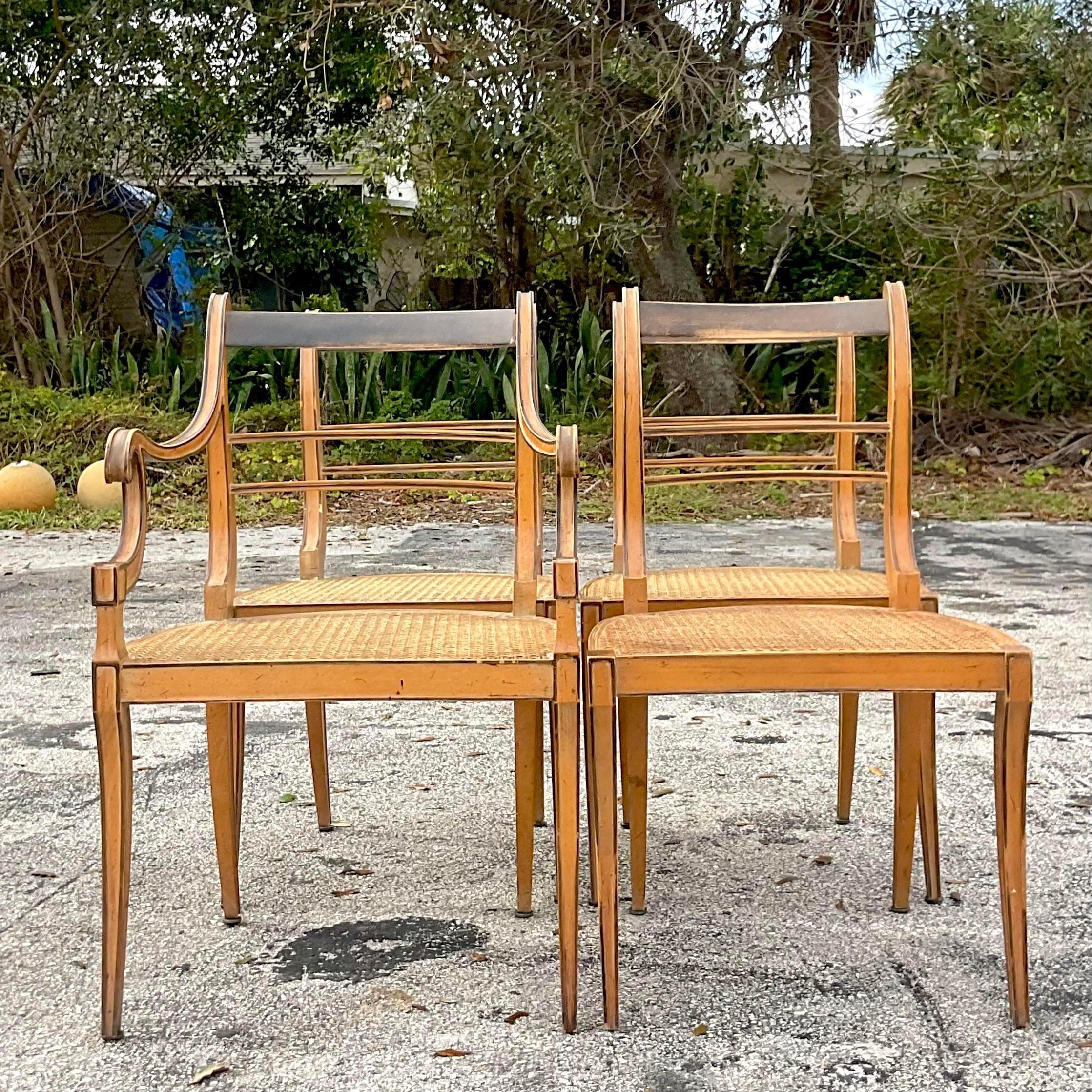 A stunning set of vintage Boho dining chairs. A chic scroll back design with handsome Saber legs. Inset cane seat panels. The perfect amount of patina from time. Acquired from a Palm Beach estate.

Arm chair 21.75x18x34.25