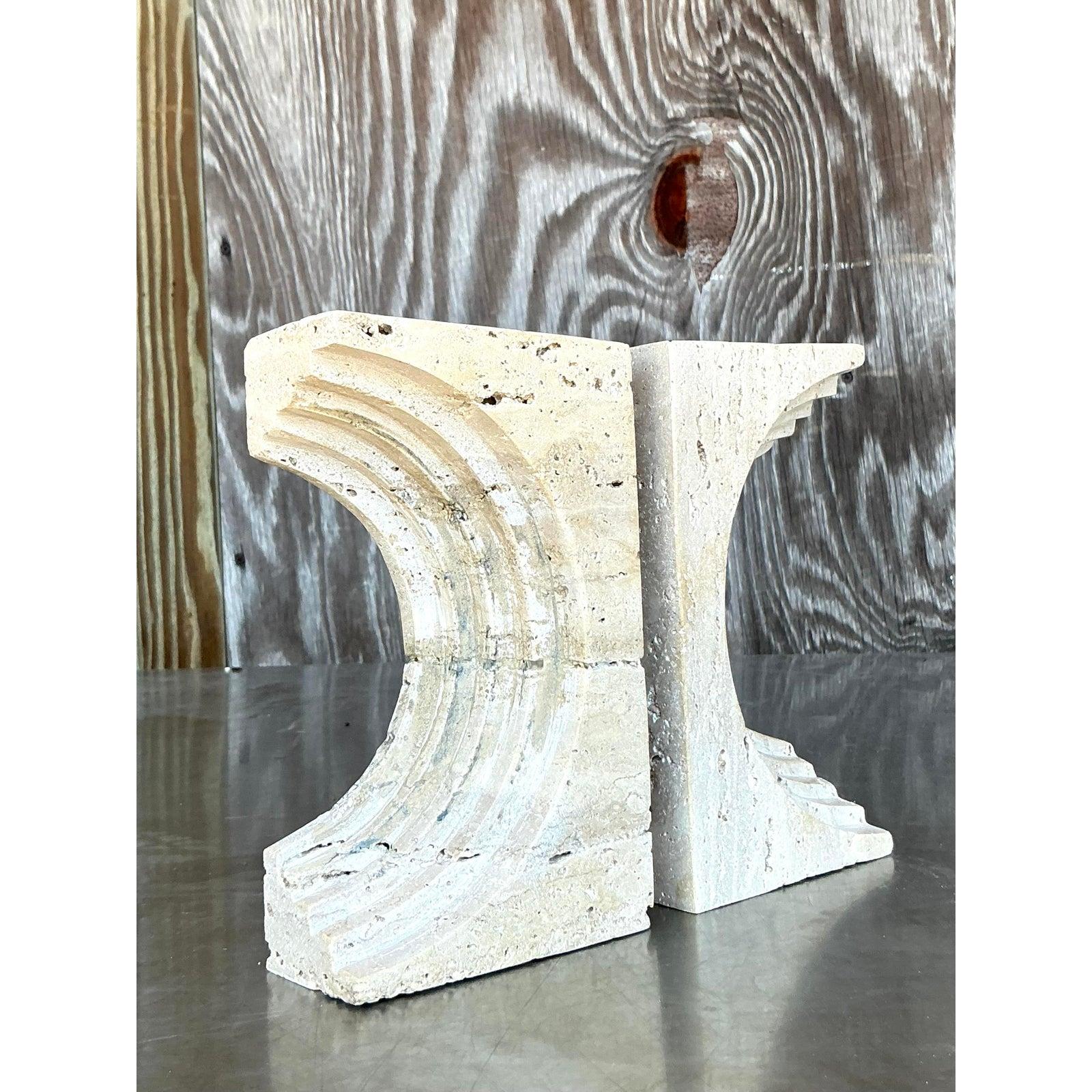 Infuse your shelves and tabletops with organic elegance and a touch of bohemian flair with this captivating set of two Vintage Boho Sculptural Travertine Bookends. Crafted from natural travertine, each bookend boasts unique textural variations and