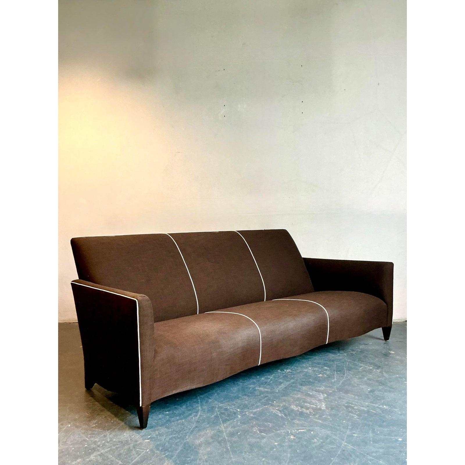 This sophisticated vintage sofa exhibits the minimalist elegance and architectural precision popularized by designers such as John Hutton for Donghia. Characterized by its sleek, clean lines and generously proportioned frame, the piece is