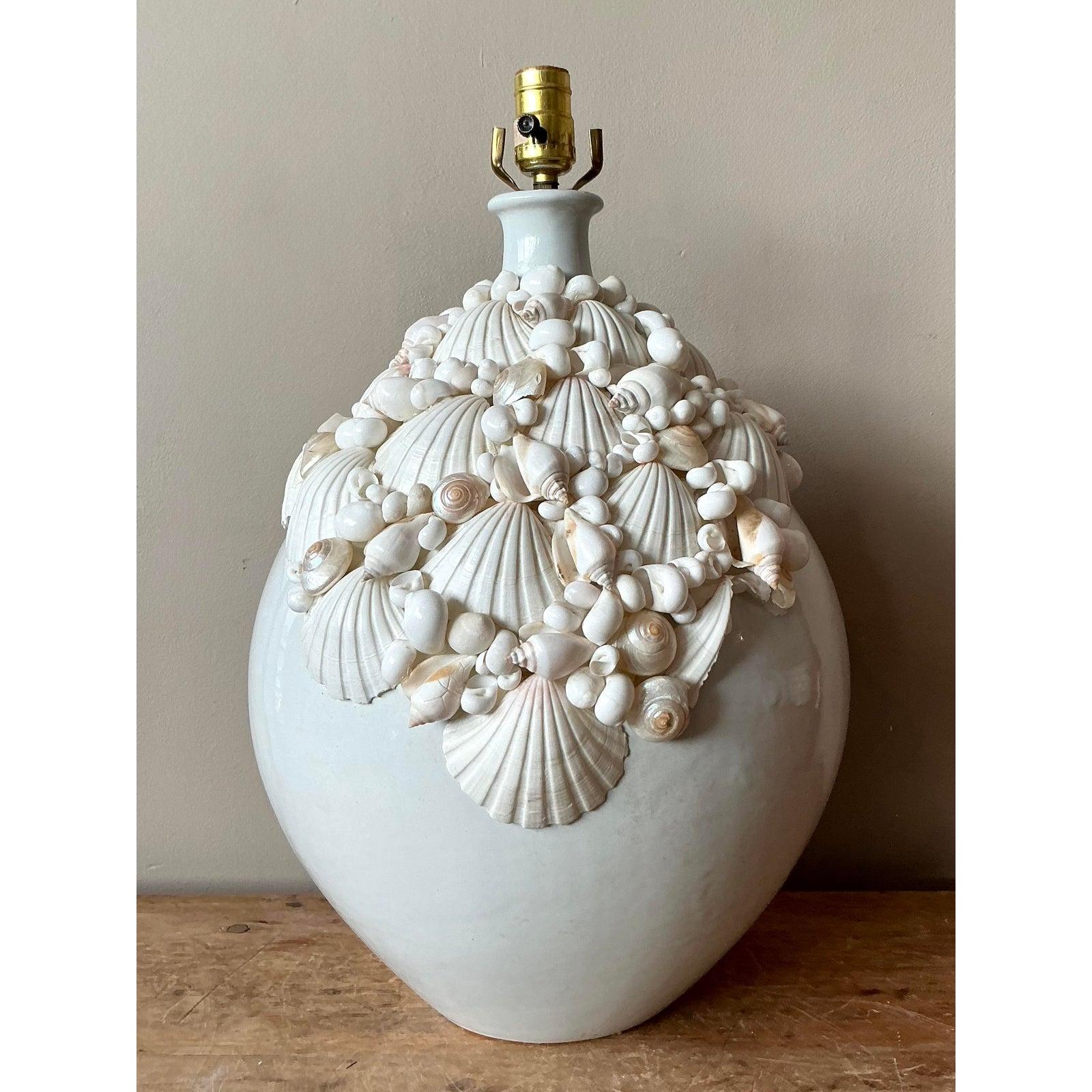 This striking vintage table lamp is a luxurious celebration of coastal artistry, perfectly embodying the glamour of Palm Beach style. The large, rounded ceramic base features a smooth, glossy white finish, beautifully contrasted by an intricate