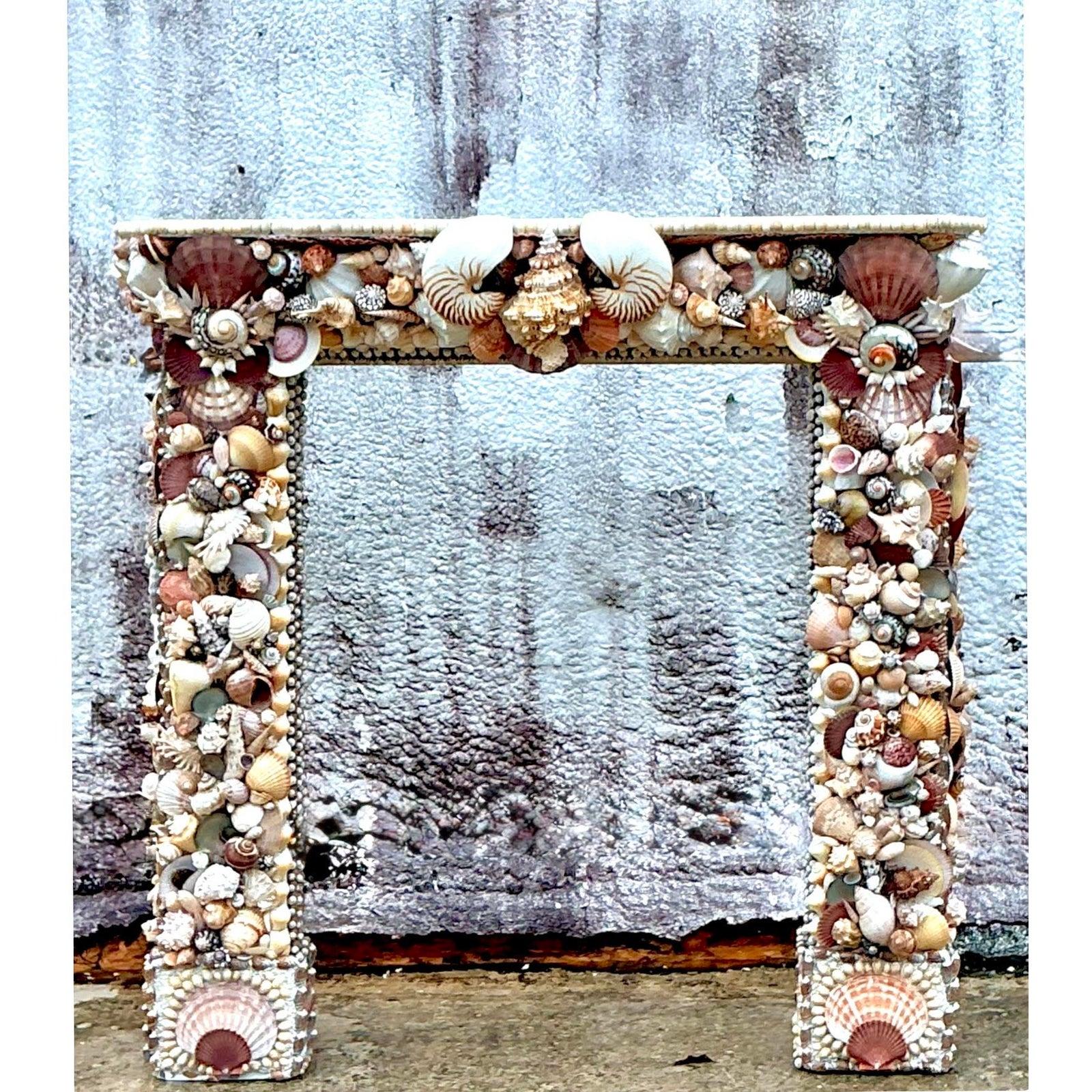 Transform your living space into a serene coastal retreat with this remarkable vintage Boho shell-encrusted fireplace surround. This unique piece is a true labor of love, meticulously adorned with an intricate array of natural seashells, creating a