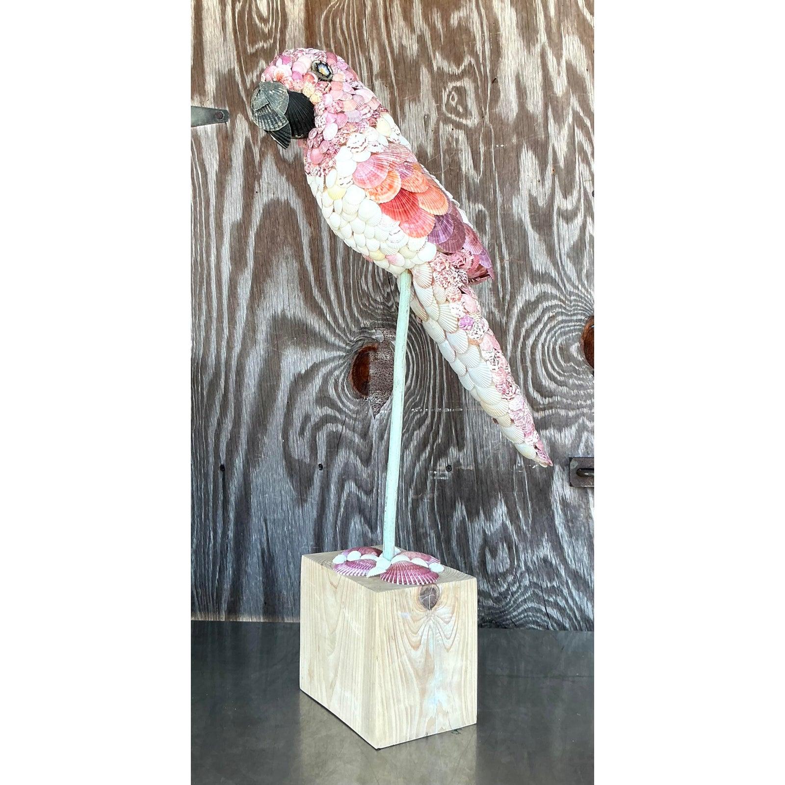 Dai un tocco di estroso fascino costiero al tuo spazio con questo splendido pappagallo vintage con conchiglie incrostate! Realizzata meticolosamente con una serie di conchiglie vere nei bellissimi colori rosa, arancione e crema, questa scultura