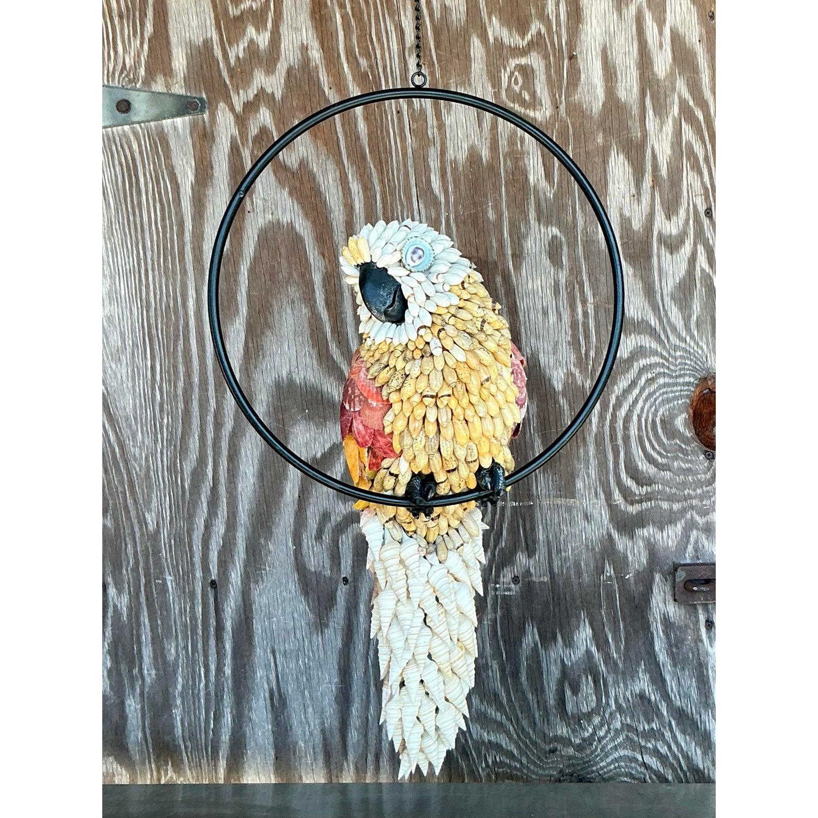 Un'accattivante opera d'arte naturale, questa scultura di uccello vintage incastonata in una conchiglia è una vera e propria testimonianza di maestria artigianale. Sospeso con grazia all'interno di un elegante cerchio di metallo nero, questo pezzo