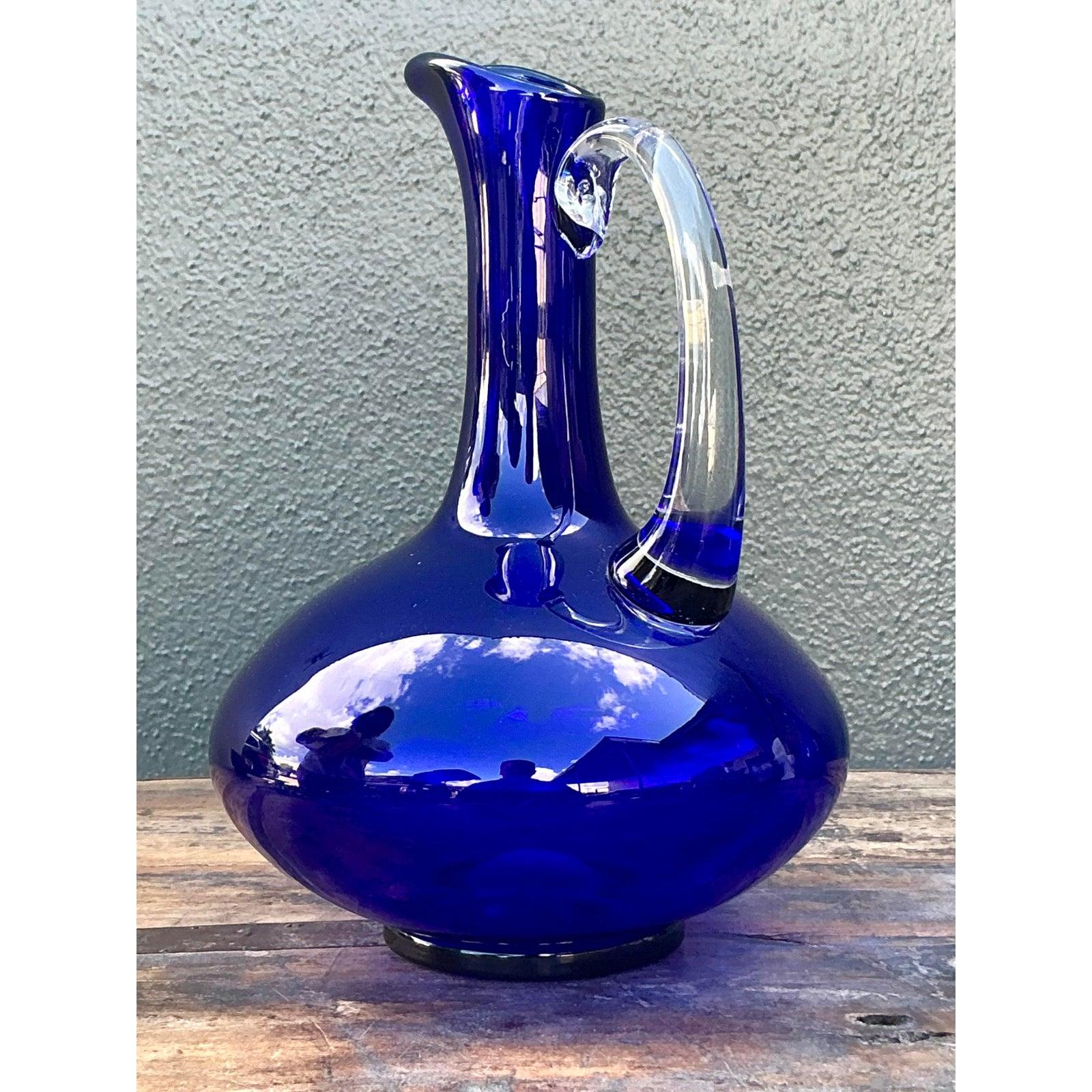 Mit diesem exquisiten, signierten Vintage-Krug aus Kunstglas setzen Sie bei Ihrer nächsten Veranstaltung ein eindrucksvolles Zeichen. Das meisterhaft mundgeblasene Gefäß hat einen tiefen, leuchtenden kobaltblauen Farbton, der das Licht mit