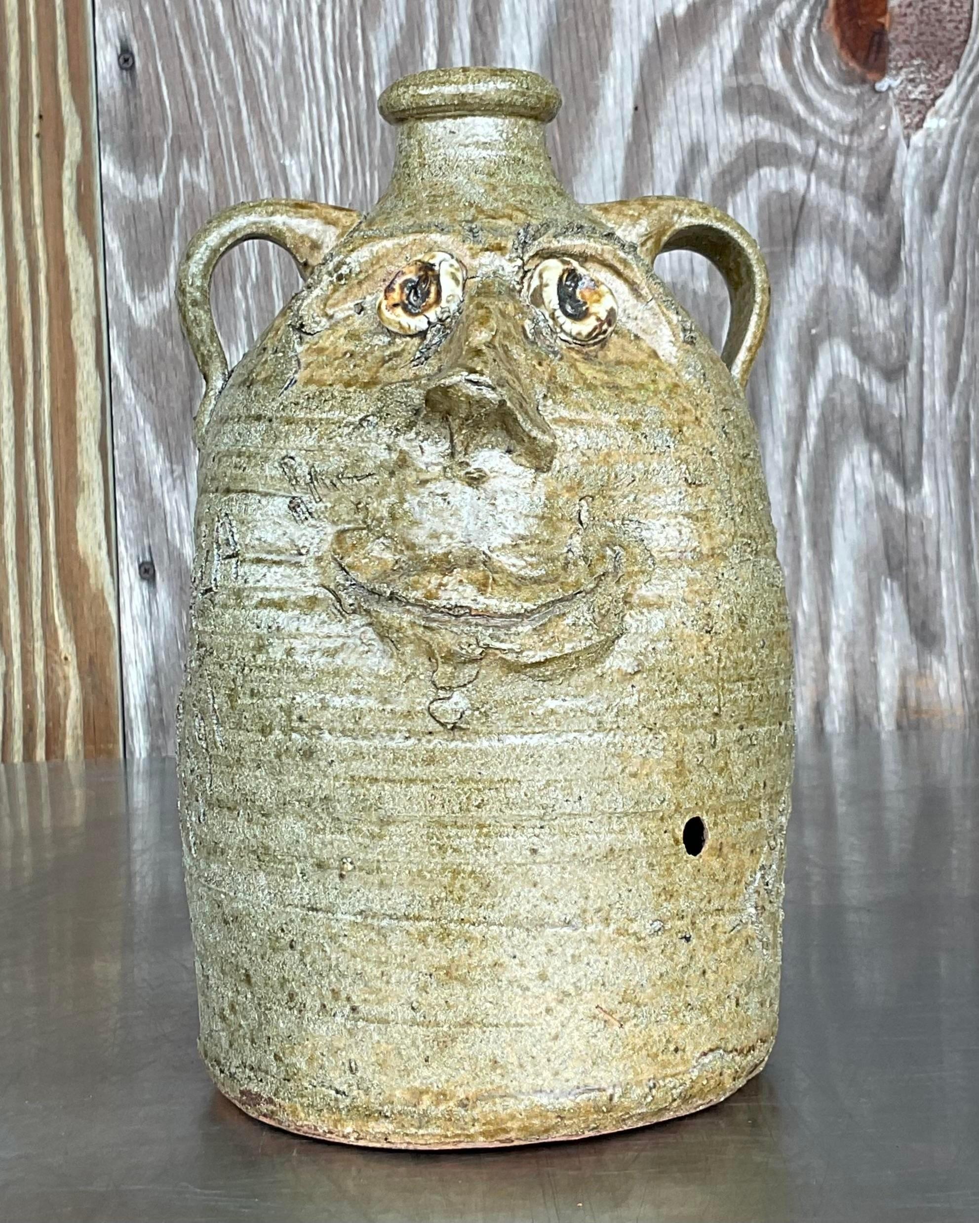 Elevate your décor with this unique Vintage Boho Signed Studio Pottery Two-Faced Jug.
Handcrafted by a skilled artist, its unique design reflects the beauty of the natural world, adding a touch of rustic elegance to any space. With its timeless