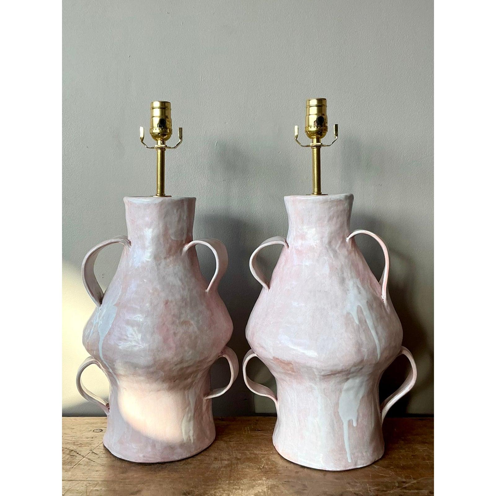 Soft, sculptural, and undeniably chic, this pair of vintage studio pottery table lamps captures the playful spirit of the Postmodern era. Hand-built using slab or coil techniques, each lamp features a unique, biomorphic amphora silhouette adorned