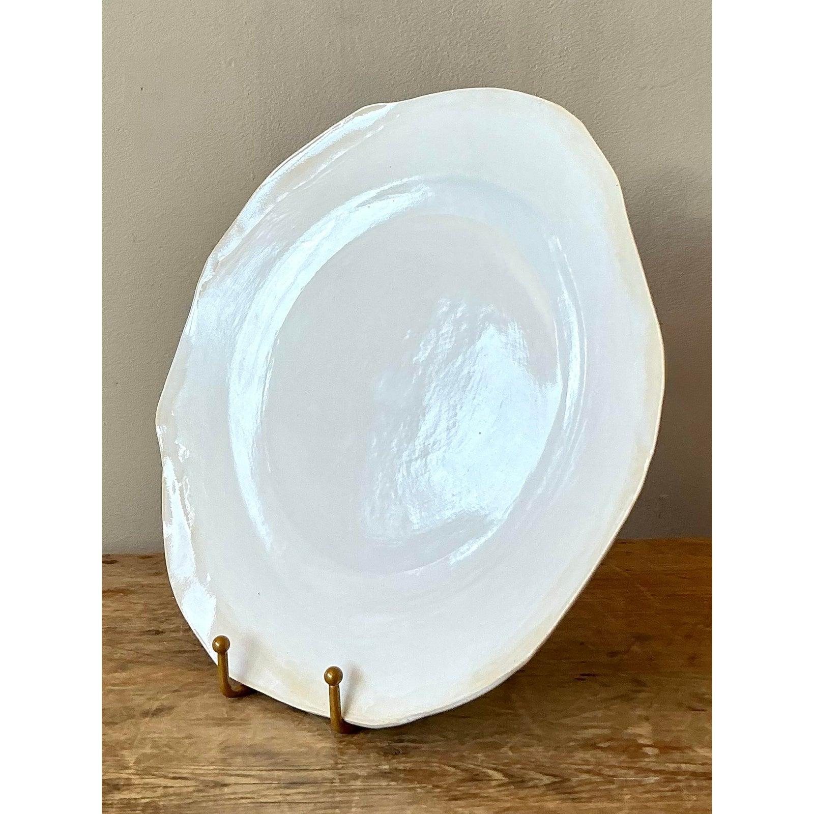Celebrate the art of the handmade with this exquisite vintage studio pottery salad plate. Expertly crafted using the slab-building technique, this piece features a delightfully organic, freeform silhouette with a gently undulating rim that sets it