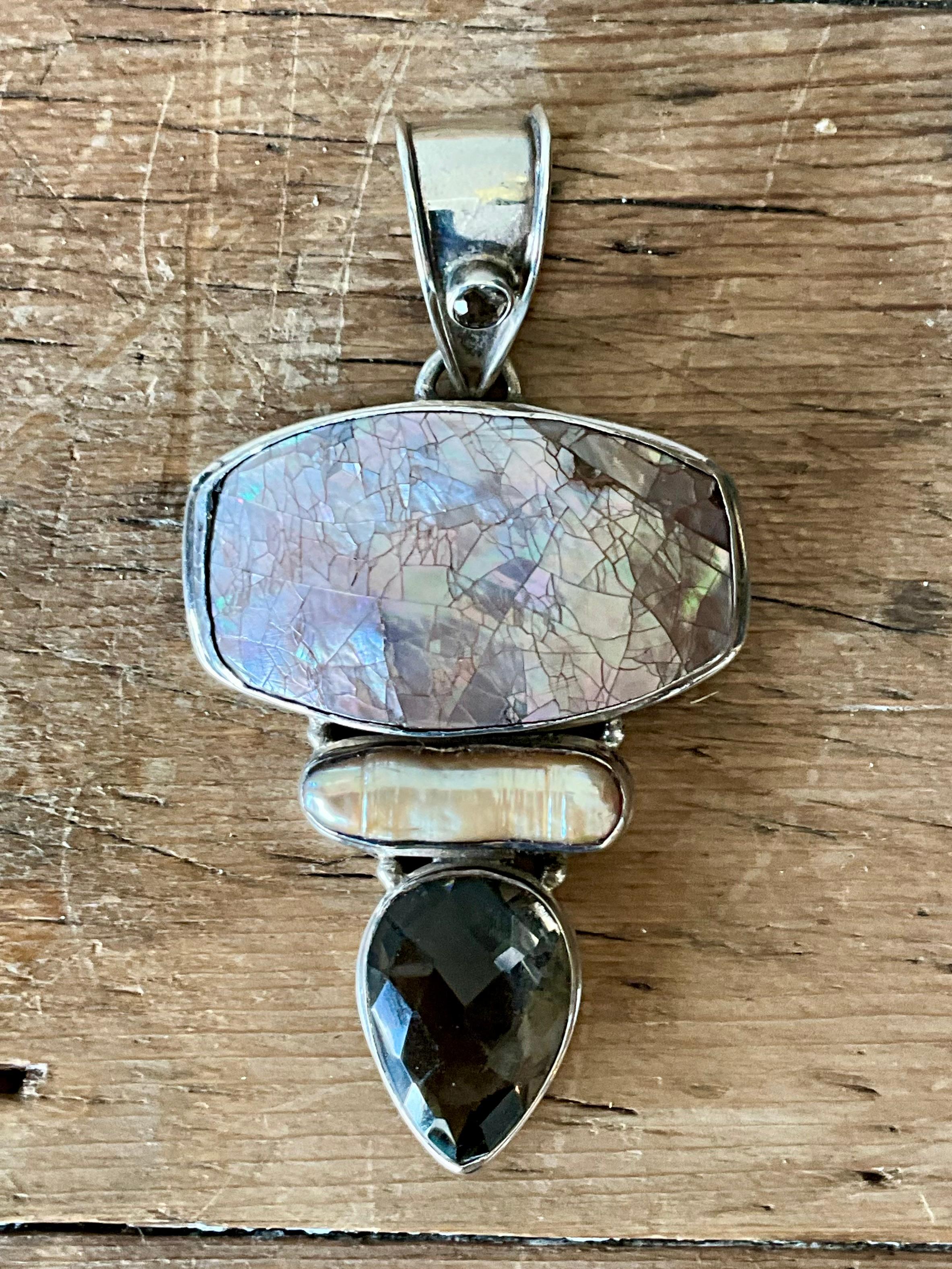 Ce pendentif Boho vintage est une fusion étonnante d'élégance naturelle et de charme éclectique, mettant en vedette un quartz fumé captivant associé à une nacre lumineuse. La profondeur riche et translucide du quartz fumé contraste magnifiquement